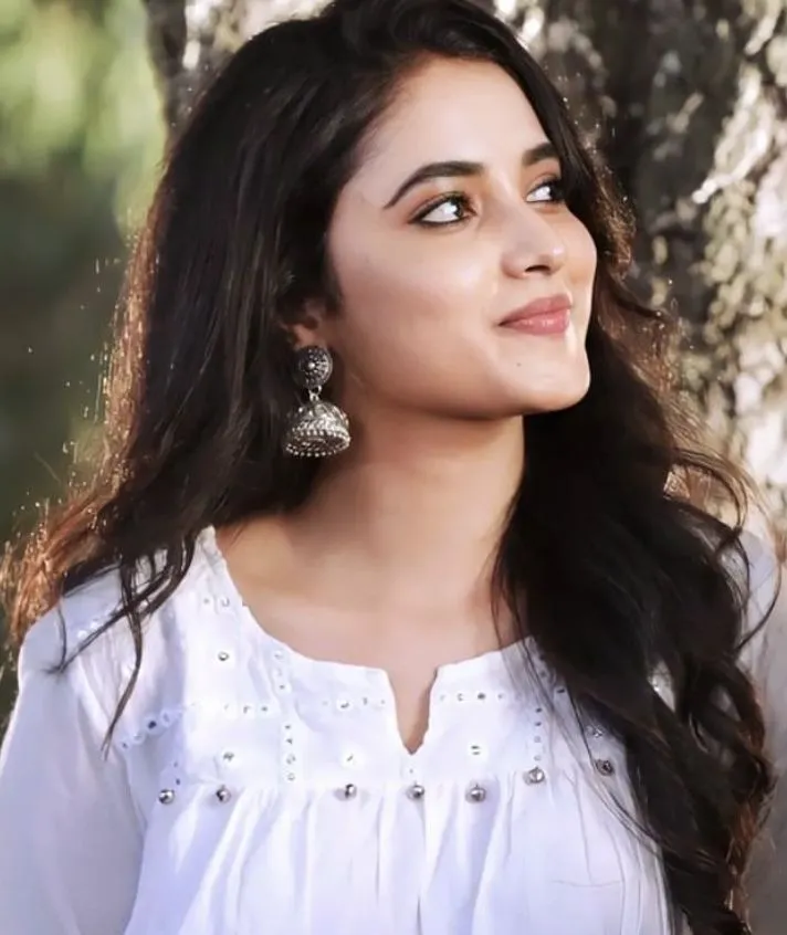 Priyanka Arul Mohan smiling in white top with natural curls
