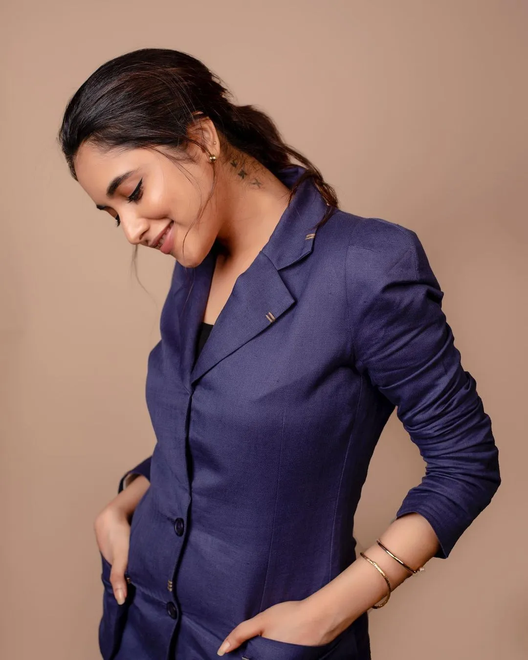 Priyanka in blue blazer looking down with gentle smile image