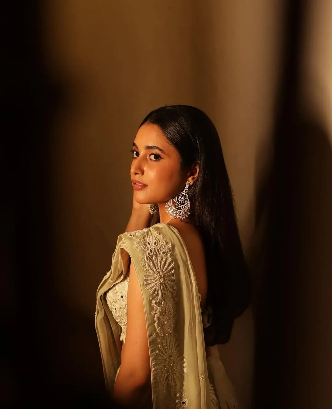 Priyanka in golden dress looking over shoulder with spotlight