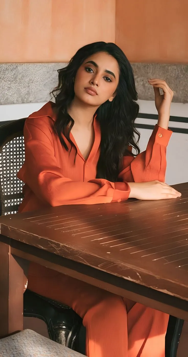Priyanka in orange outfit sitting on the wooden table HD