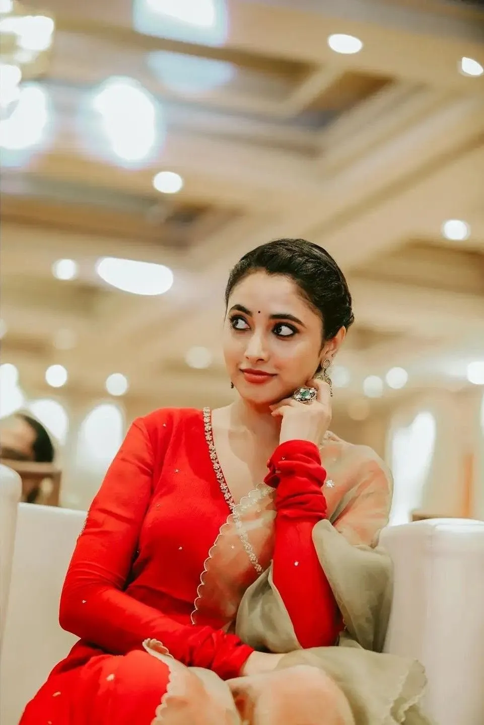 Priyanka in red dress hand on chin indoors free Wallpaper