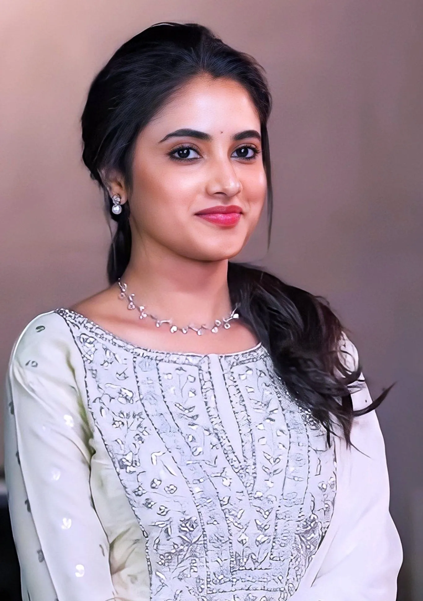 Priyanka Mohan Against a Pink Backdrop Wearing a White Dress