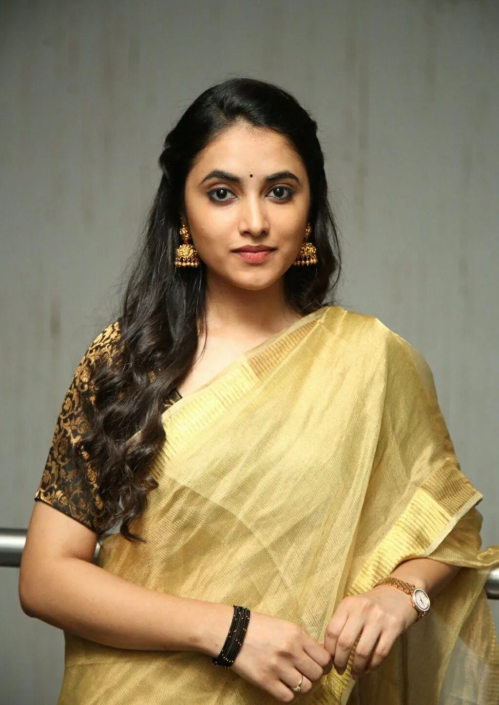 Priyanka Mohan in a Golden Saree Standing Near Studio Wall