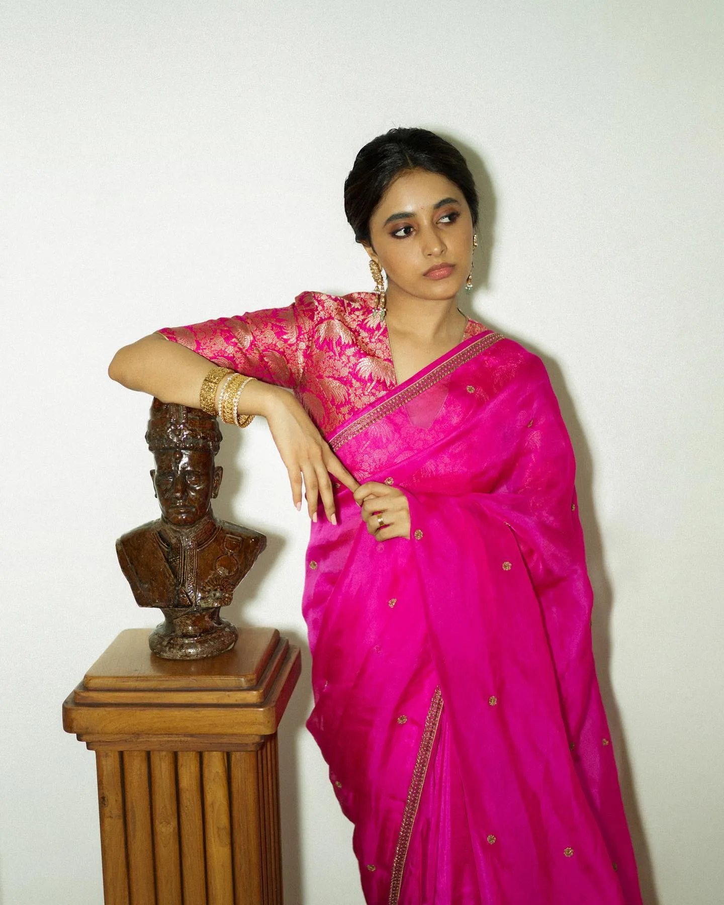 Priyanka Mohan in a Pink Saree with Her Hand on a Statue