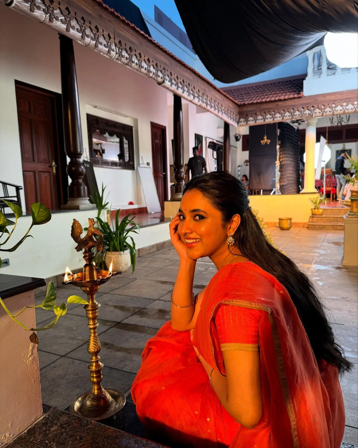 Priyanka Mohan in a Red Saree Sitting Near the Oil Lamp