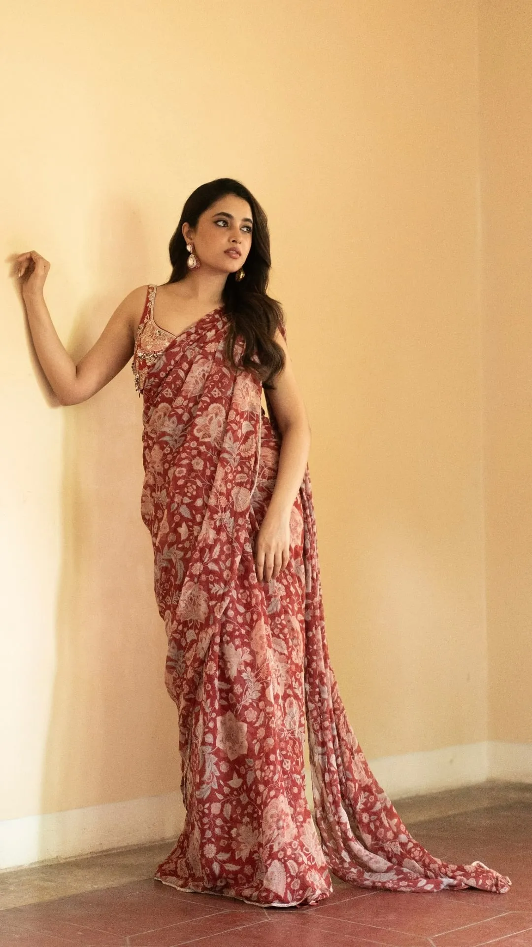 Priyanka Mohan in a Red Saree Standing Near the Studio Wall