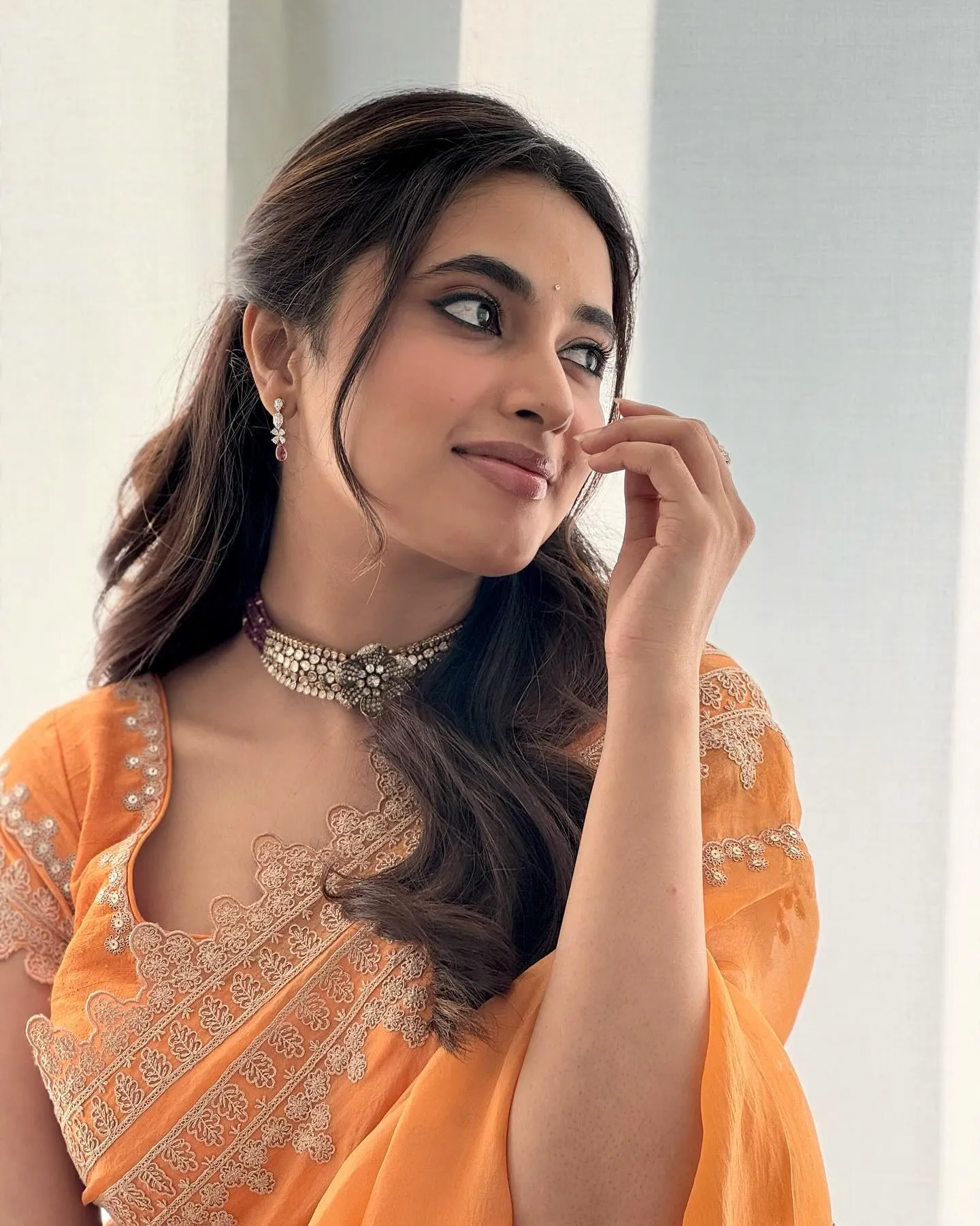 Priyanka Mohan in an Orange Saree with Her Hand on Her Face