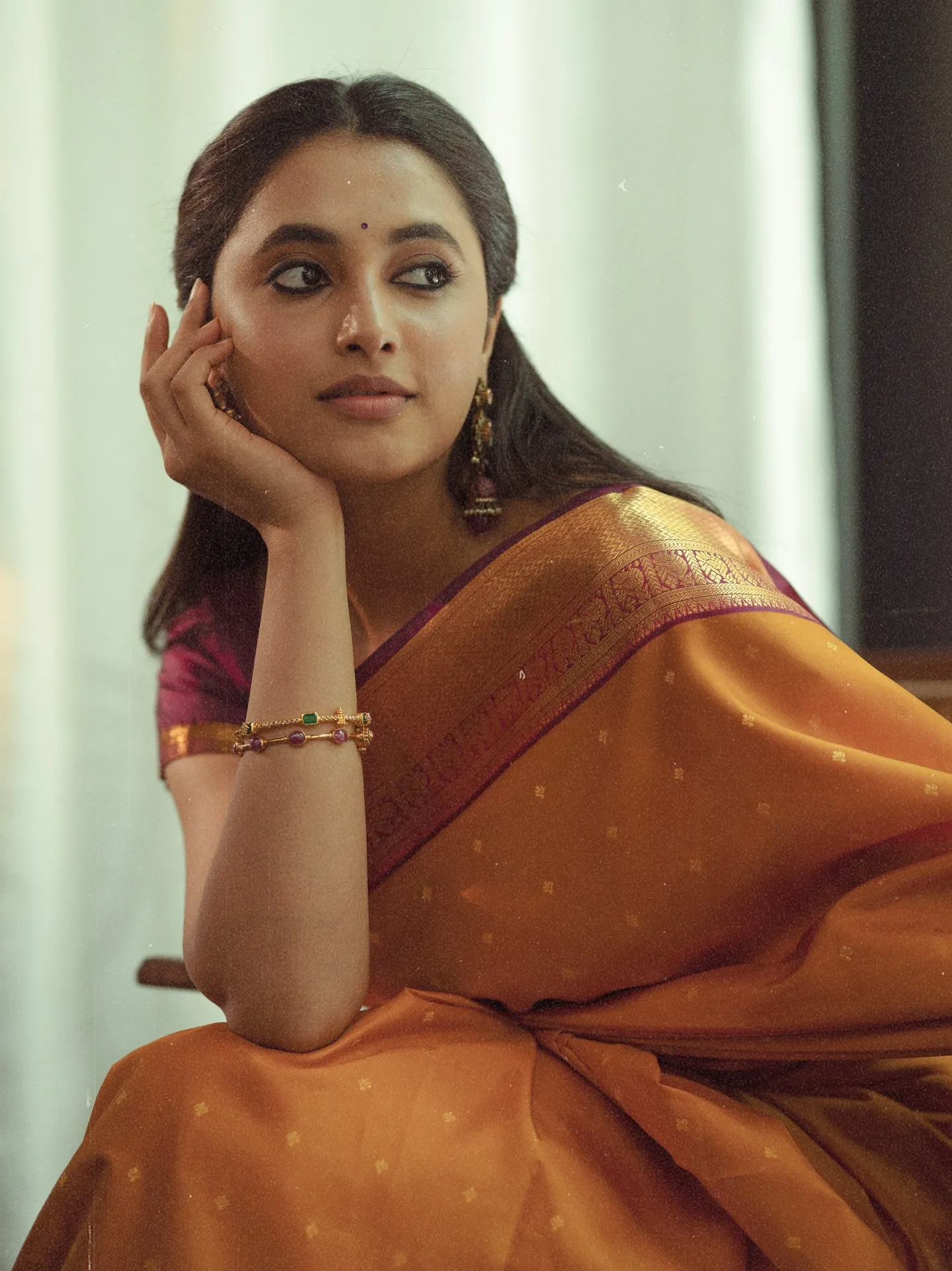 Priyanka Mohan in an Orange Sitting with Her Hand on Cheek