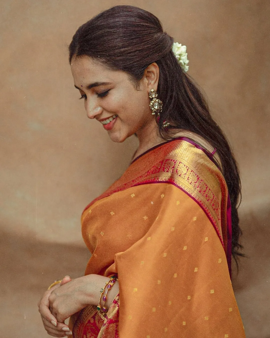 Priyanka Mohan in Orange Saree in Side Pose with Eyes Closed
