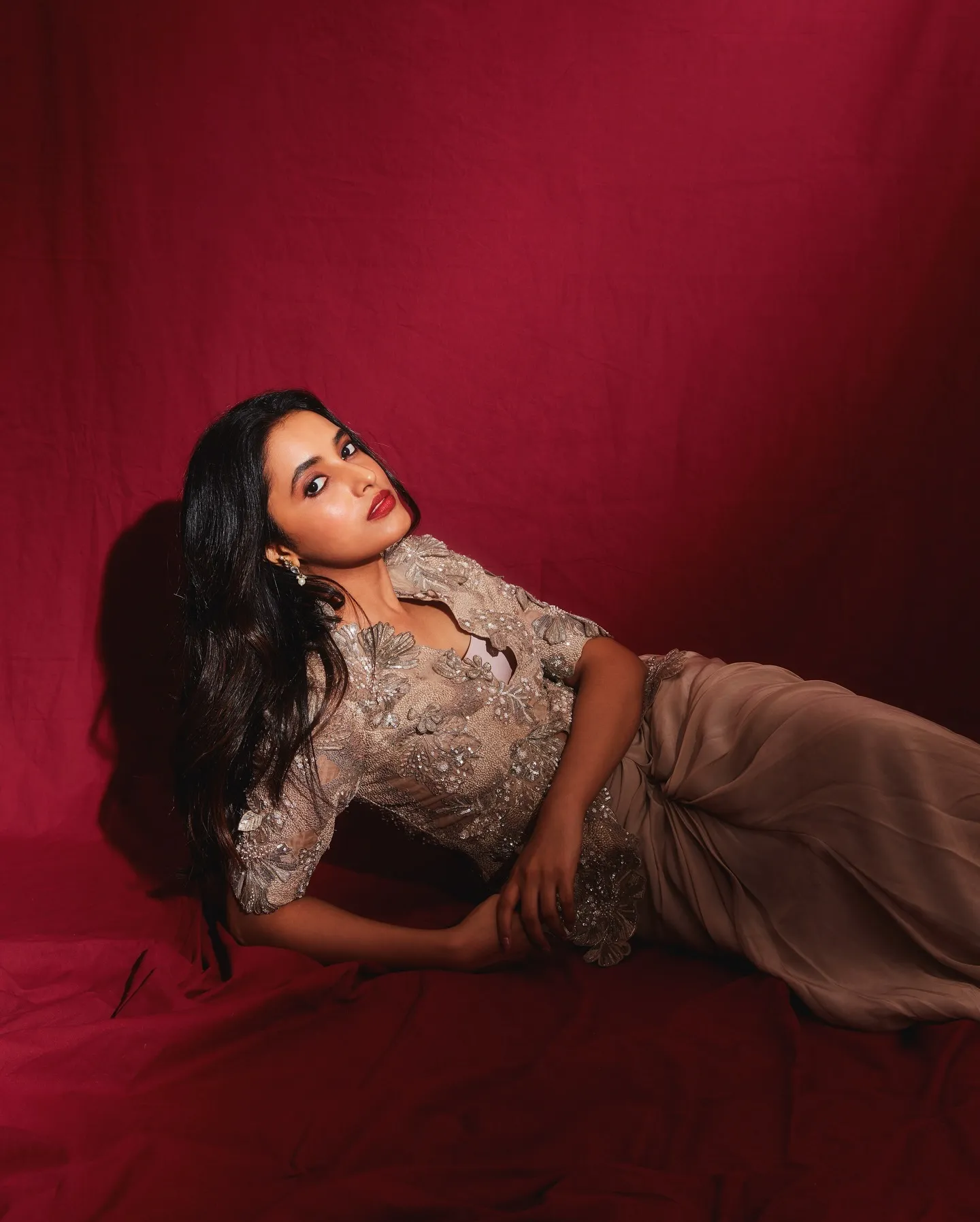 Priyanka Mohan Lying on the Floor with a Maroon Background