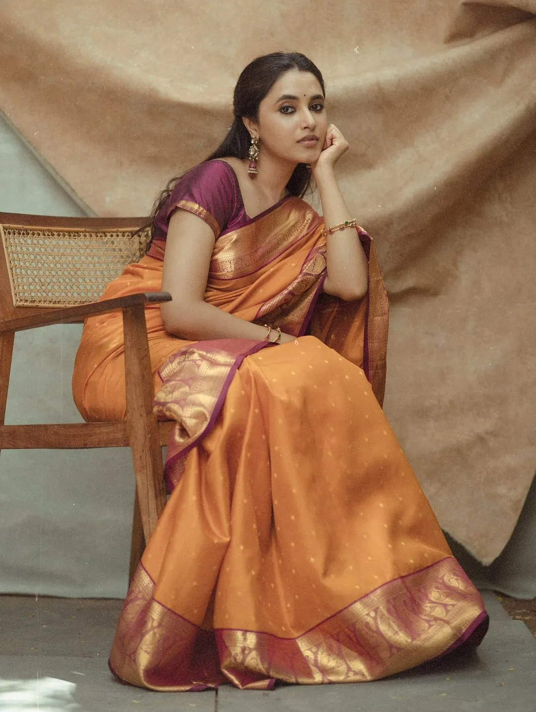 Priyanka Mohan Sitting in a Wooden Chair Near Studio Curtain