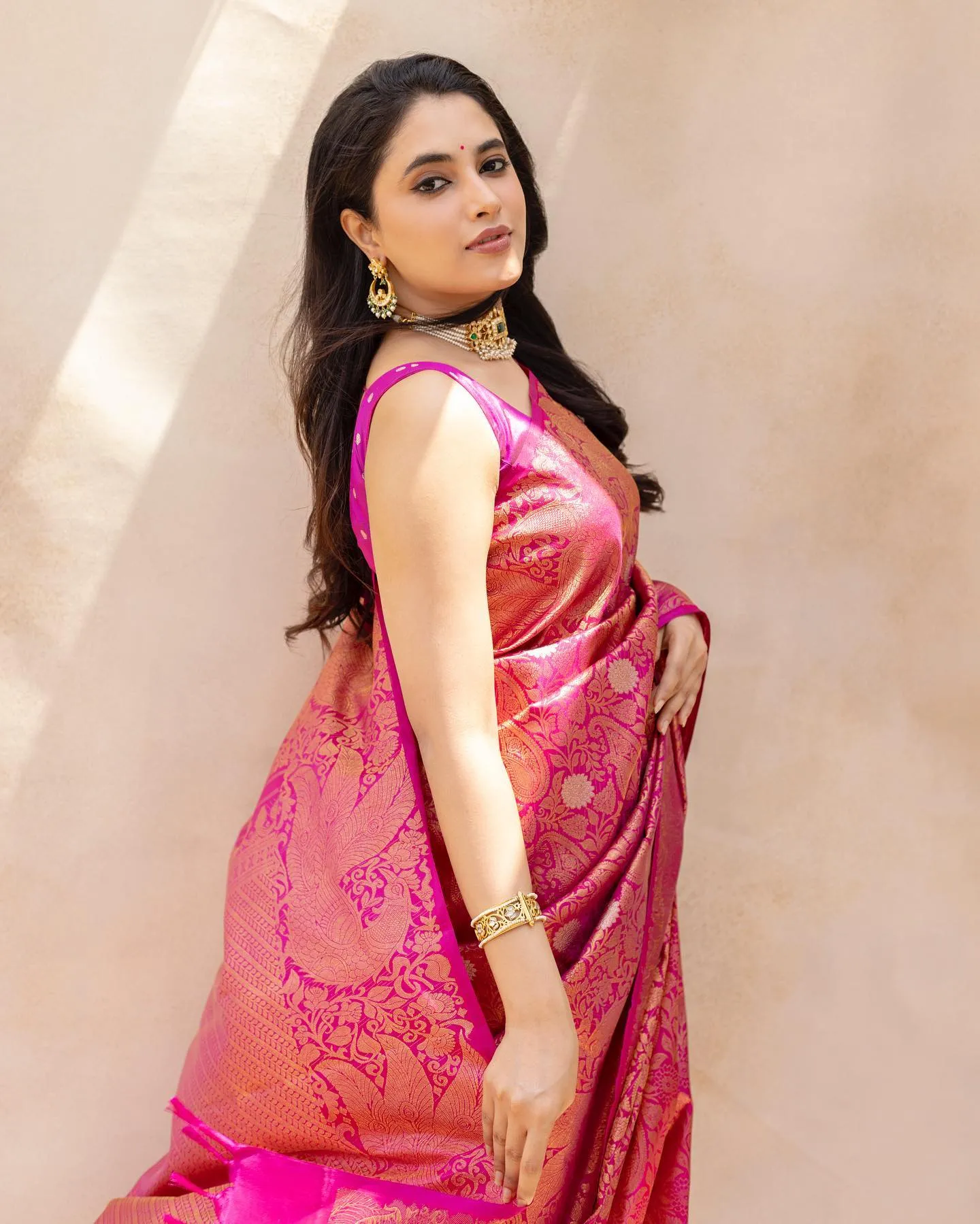 Priyanka Mohan Standing Near White Wall Wearing a Pink Saree