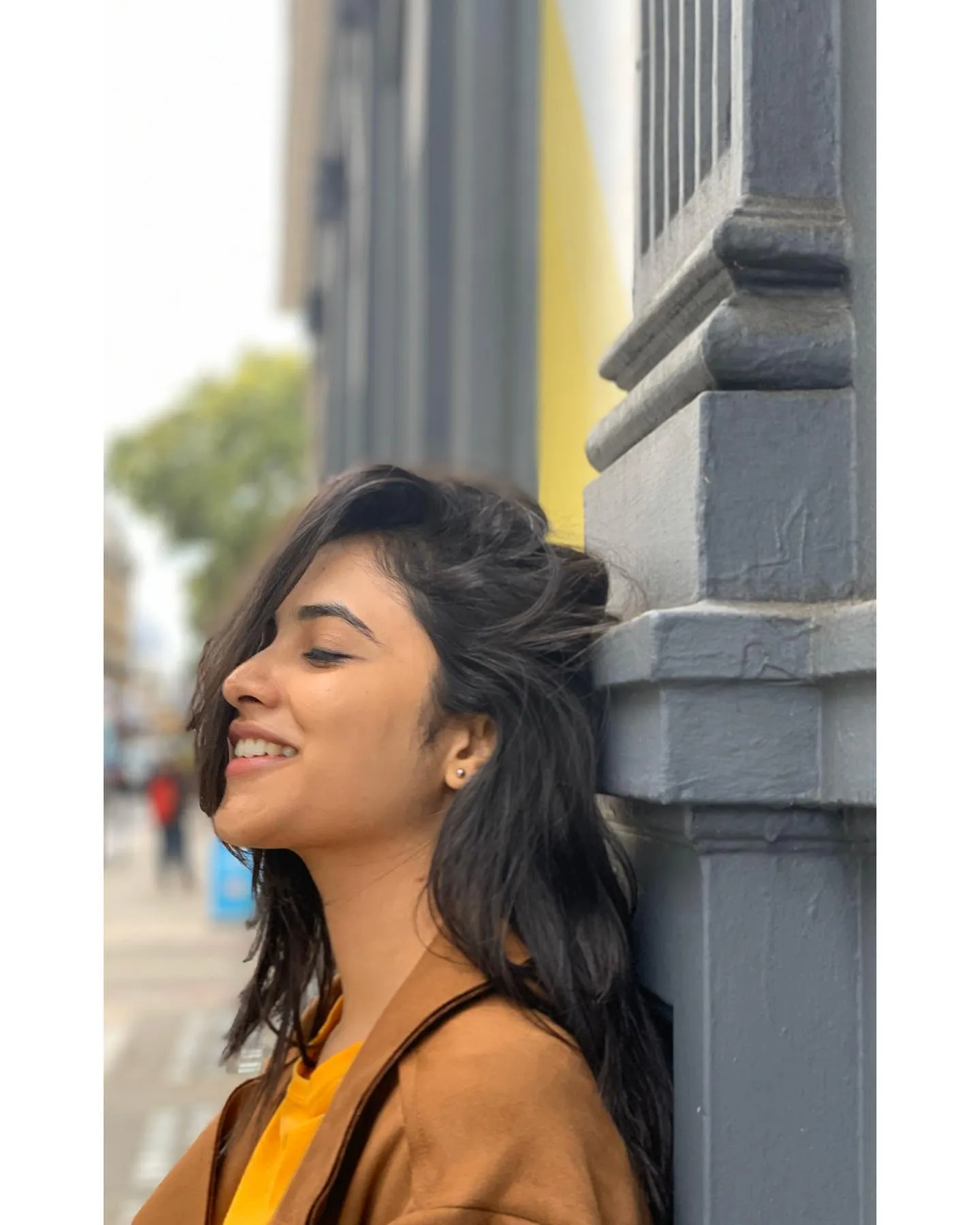 Priyanka smiling near the wall in cozy mustard outfit image