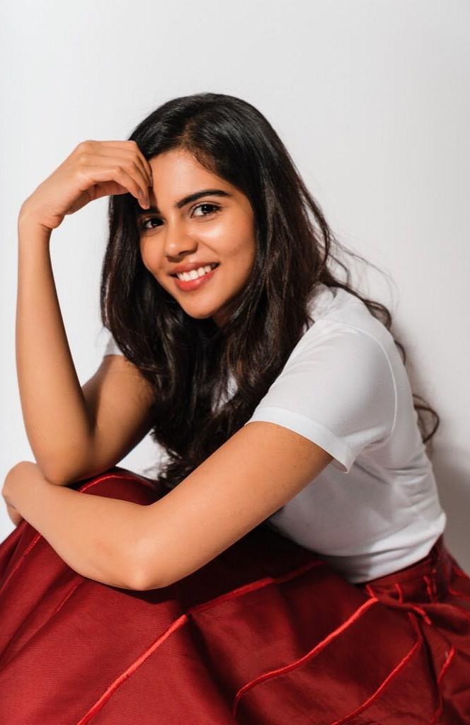 Casual Kalyani in White Tshirt Sitting and Smiling Image