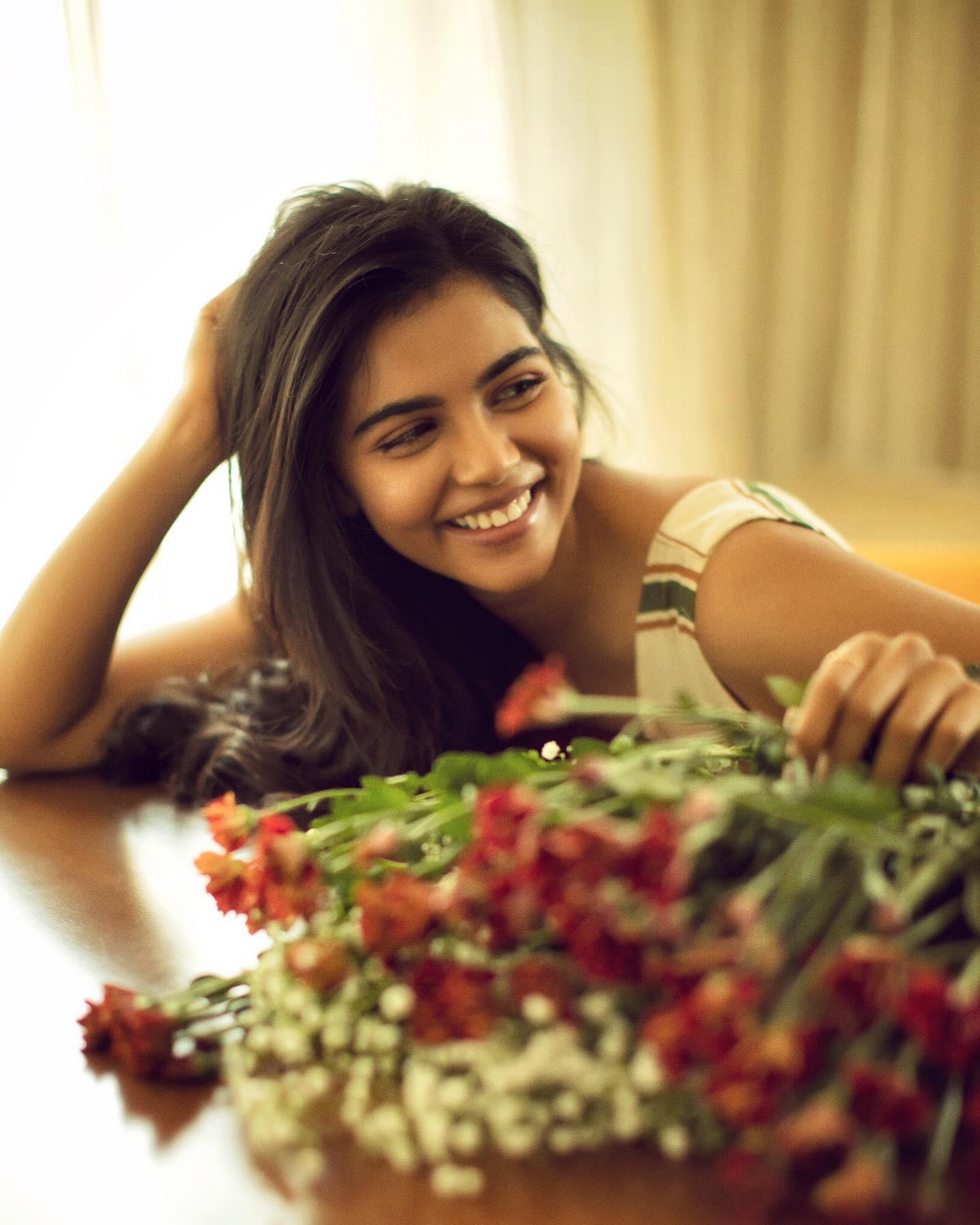 Photo of Kalyani Priyadarshan Sitting at Table with Flowers