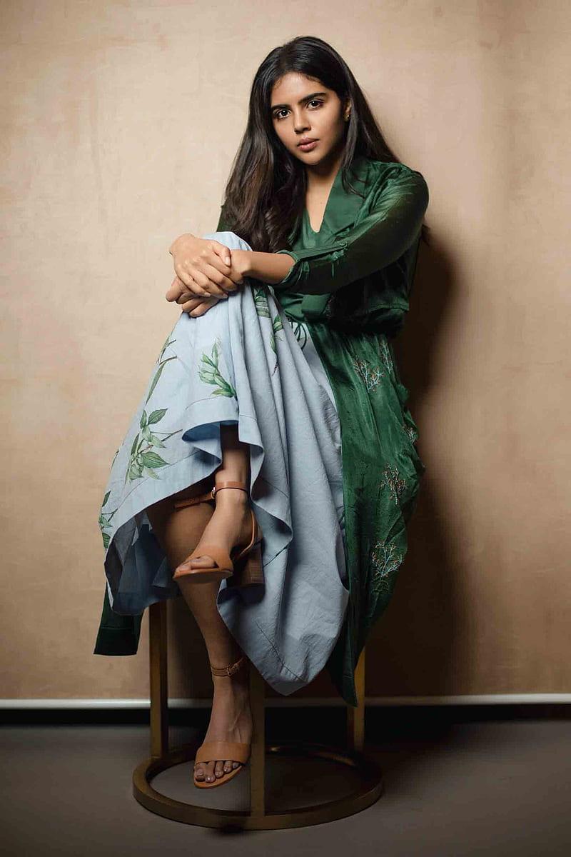 Kalyani in Green Dress Sitting with Legs Crossed Image