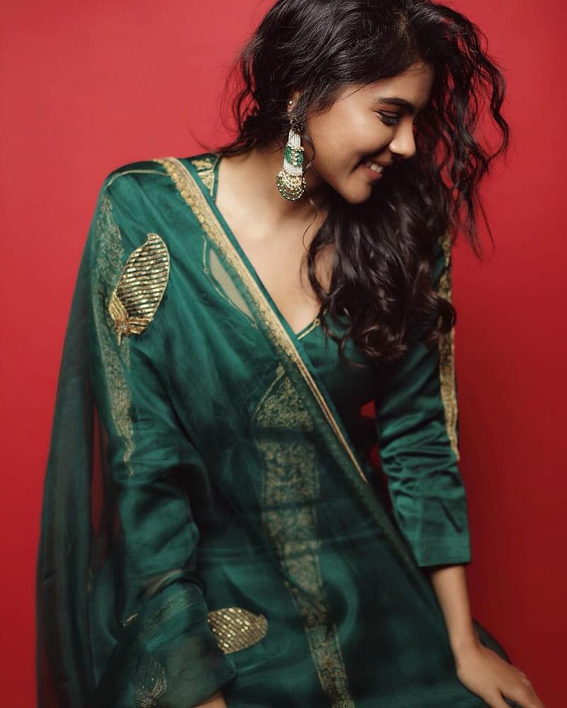 Kalyani in Green Outfit Smiling on Red Background Photo