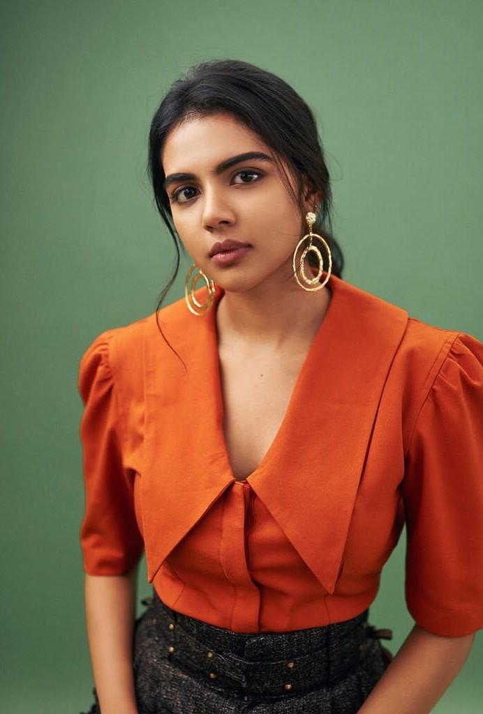 Kalyani in Orange Blouse with Earrings and Green Wall Photo