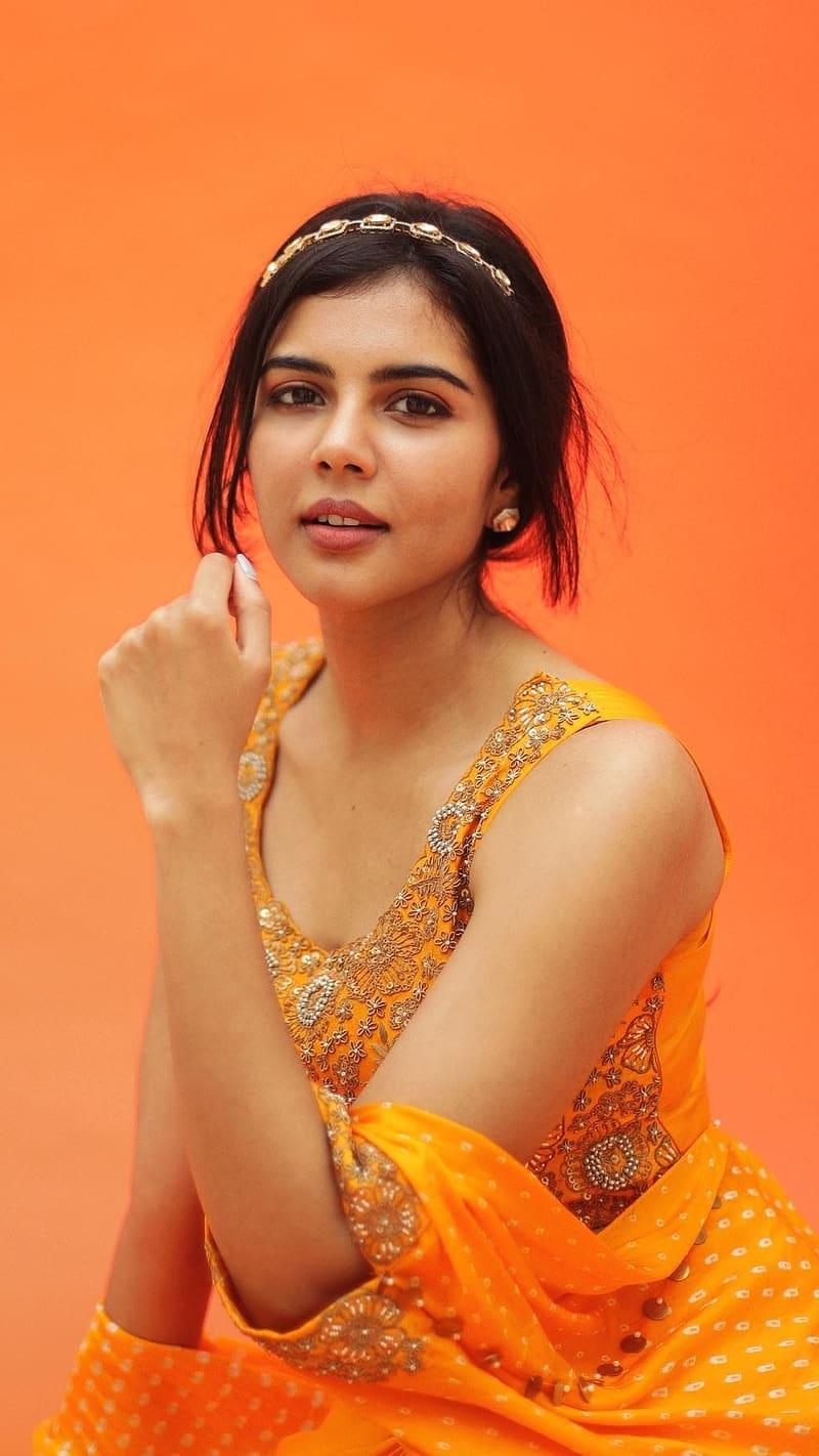 Kalyani in Orange Outfit Smiling on Orange Background Pic