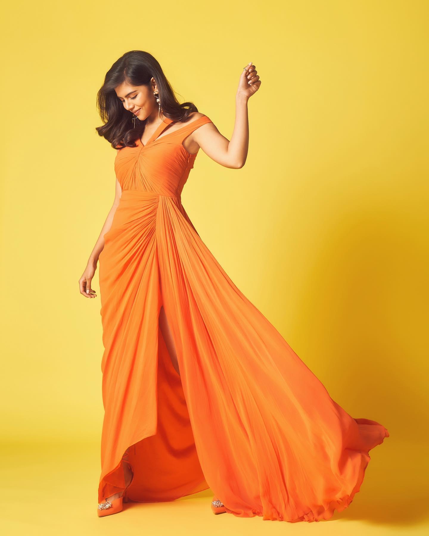 Kalyani Posing in Flowing Orange Dress Mobile Wallpaper