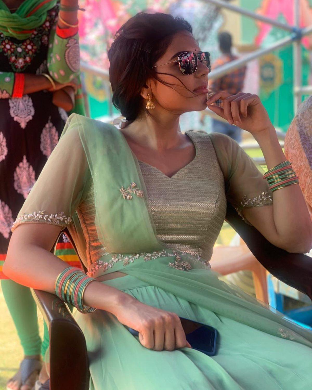 Kalyani Priyadarshan in Green Dress Sitting on Chair Photo