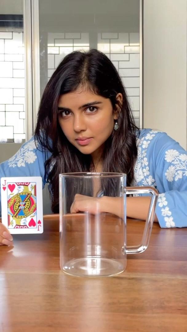 Kalyani in Blue Outfit at Table with Glass and Card Image