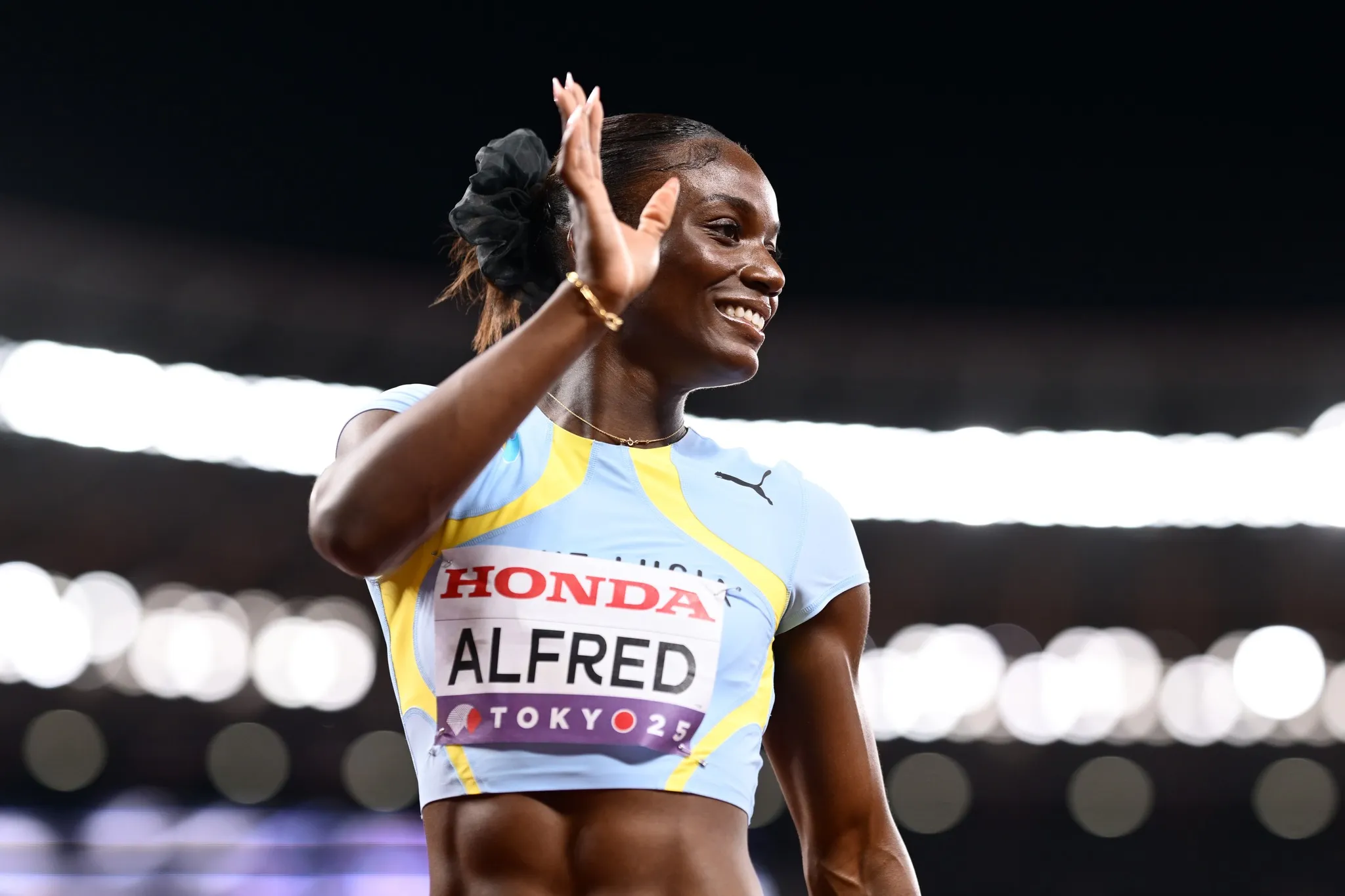 Julien Alfred waves proudly after finishing sprinting event