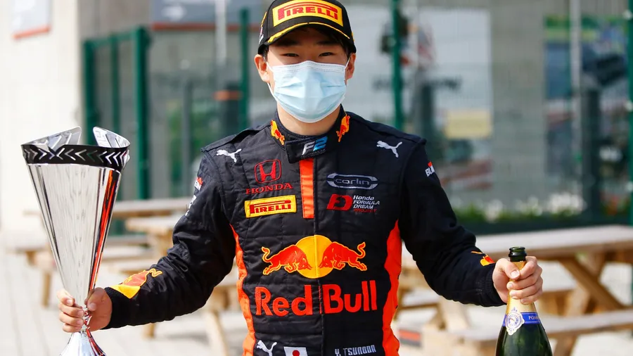 Yuki Tsunoda Celebrates Victory with Trophy in Race Gear