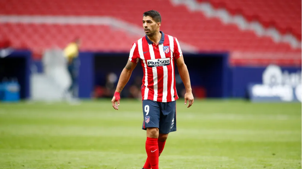 Luis Suarez walks on field in Atletico Madrid red jersey