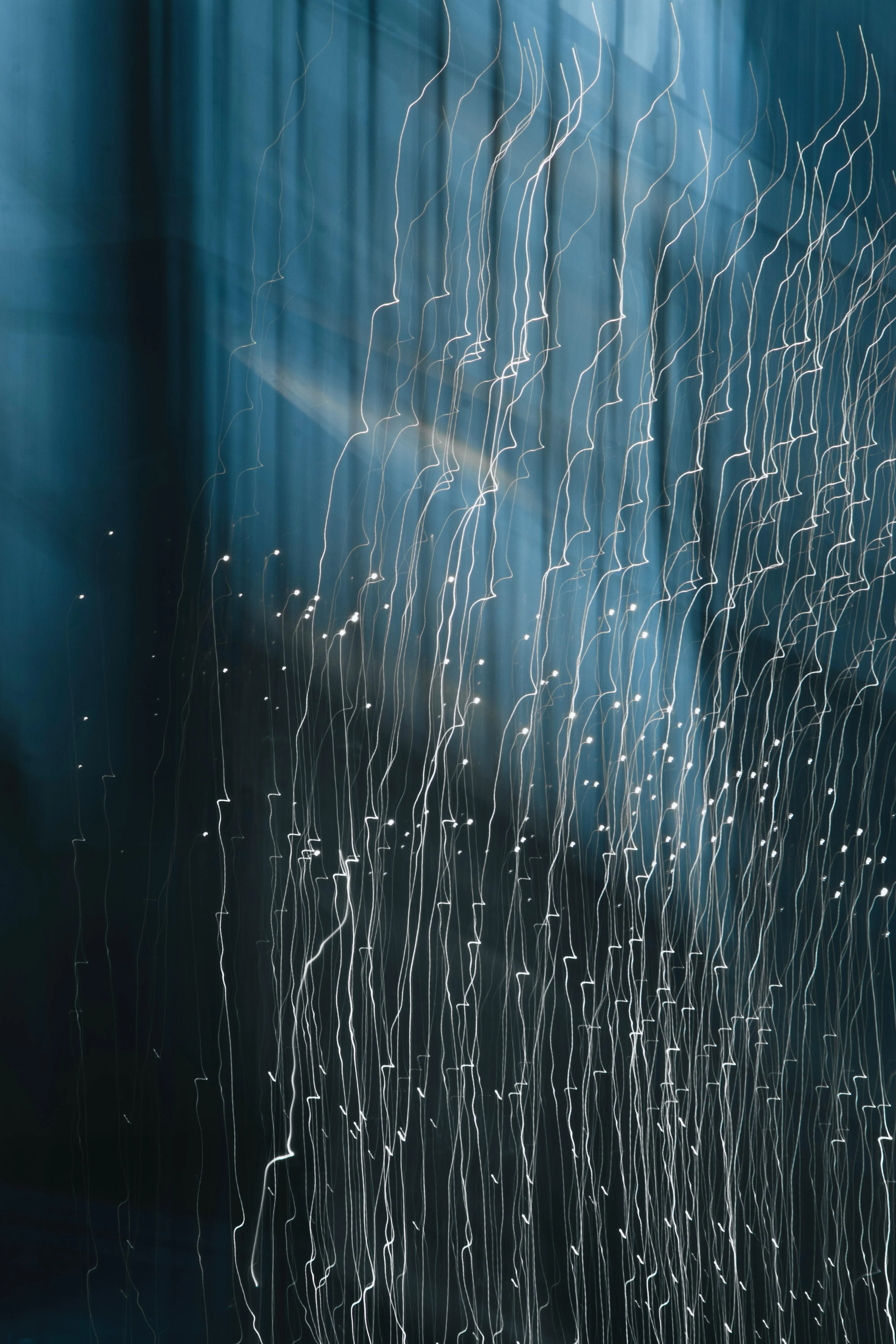 Abstract Motion of Lights Creating Vertical Streaks on Blue