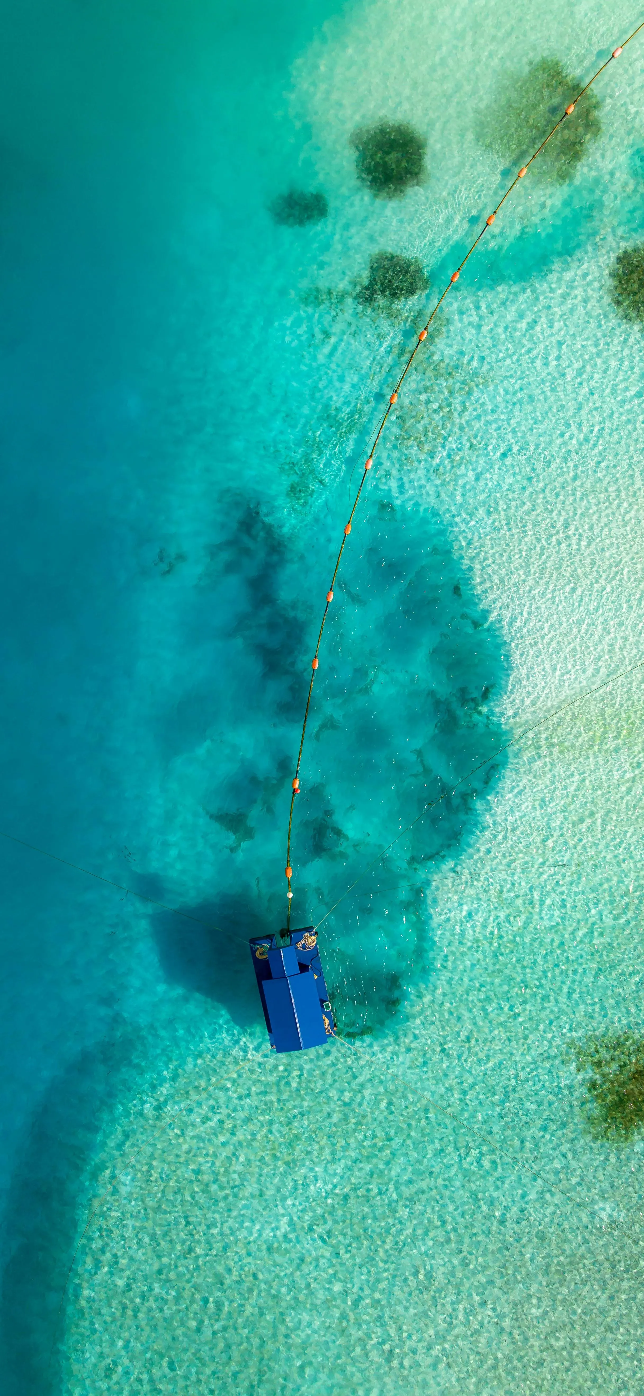 Aerial Photo of Small Cabin on Clear Turquoise Water