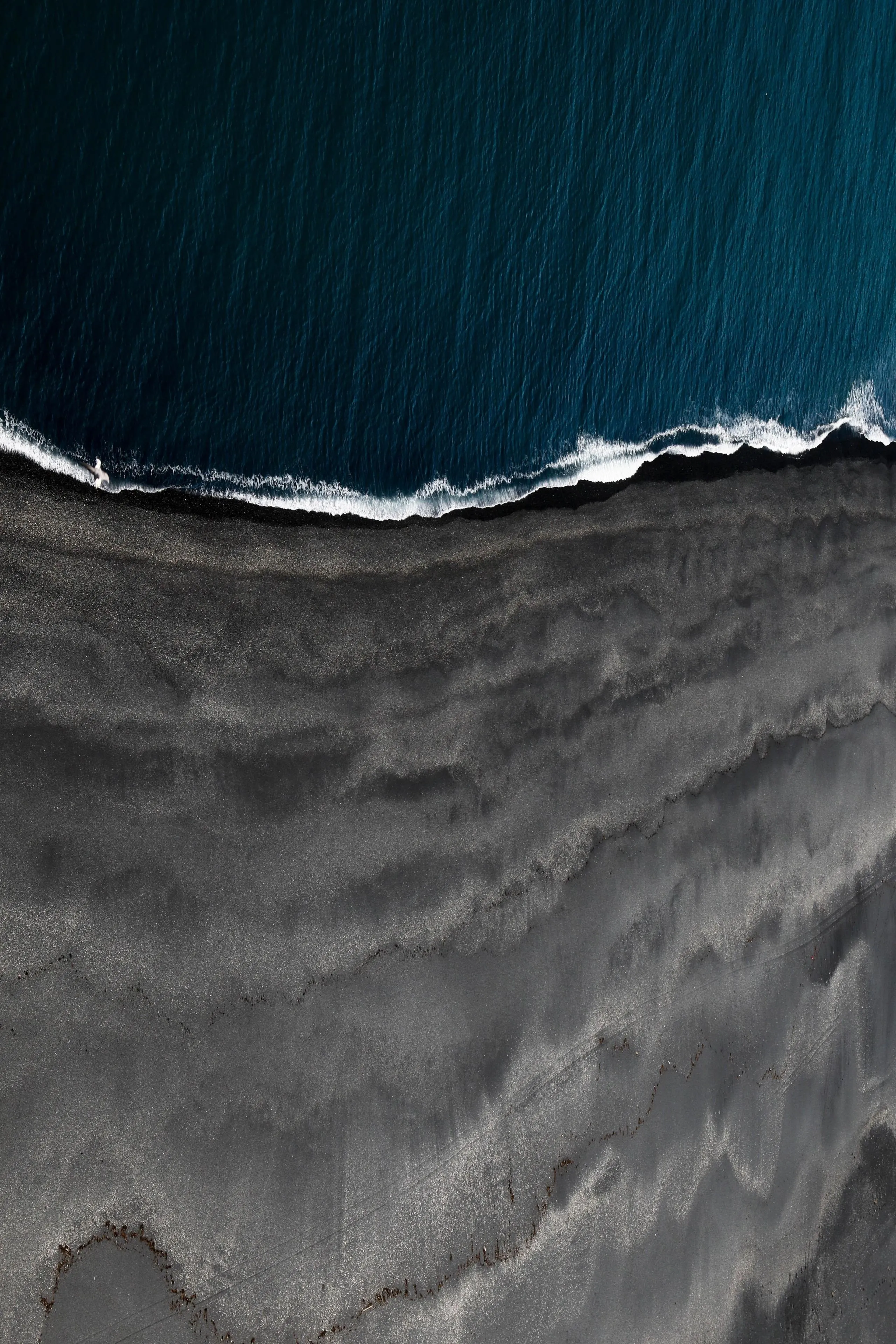 Aerial View of Dark Beach with Waves Crashing on Shore