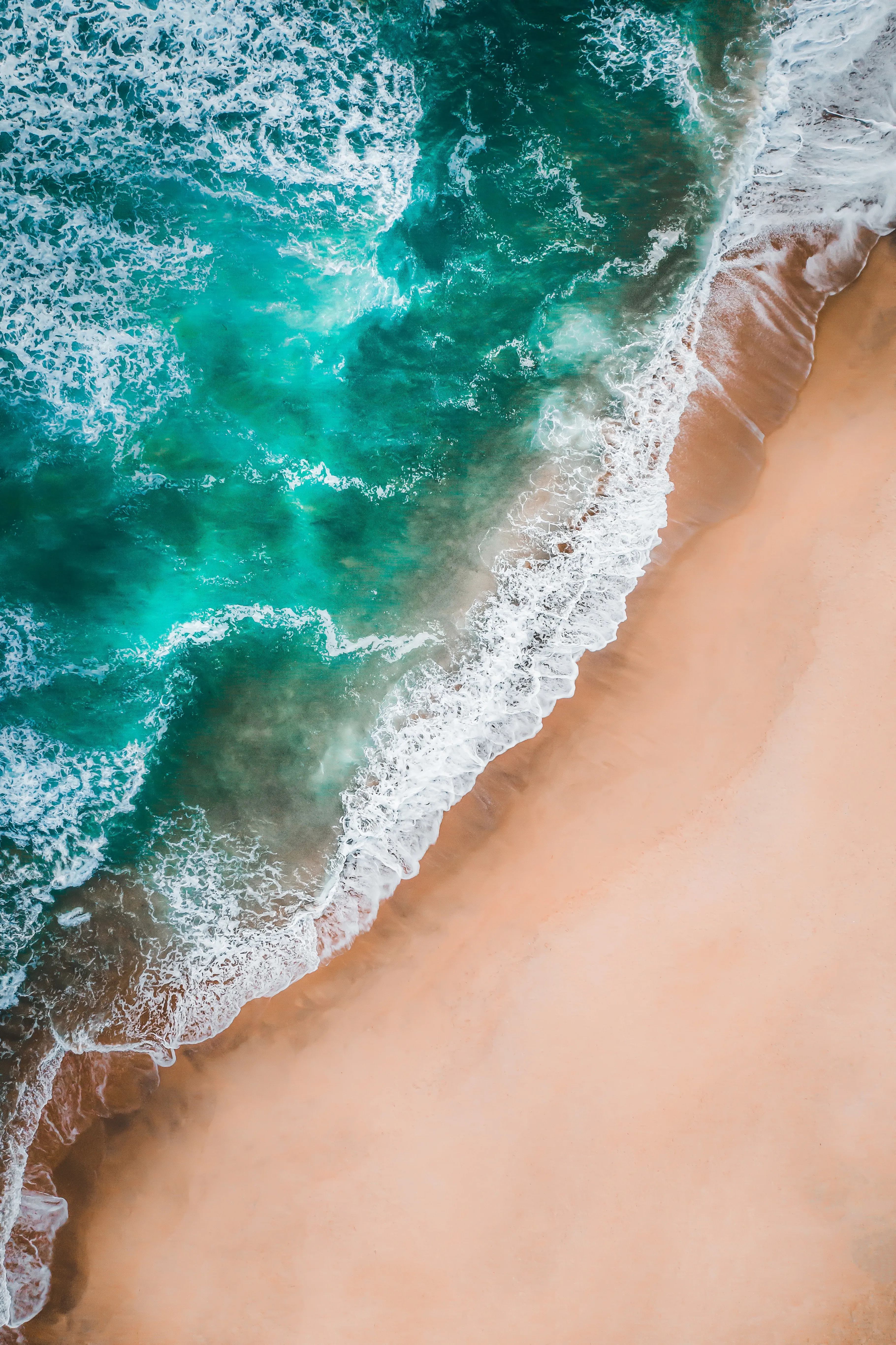 Aerial View of Ocean Waves on Sandy Beach Wallpaper