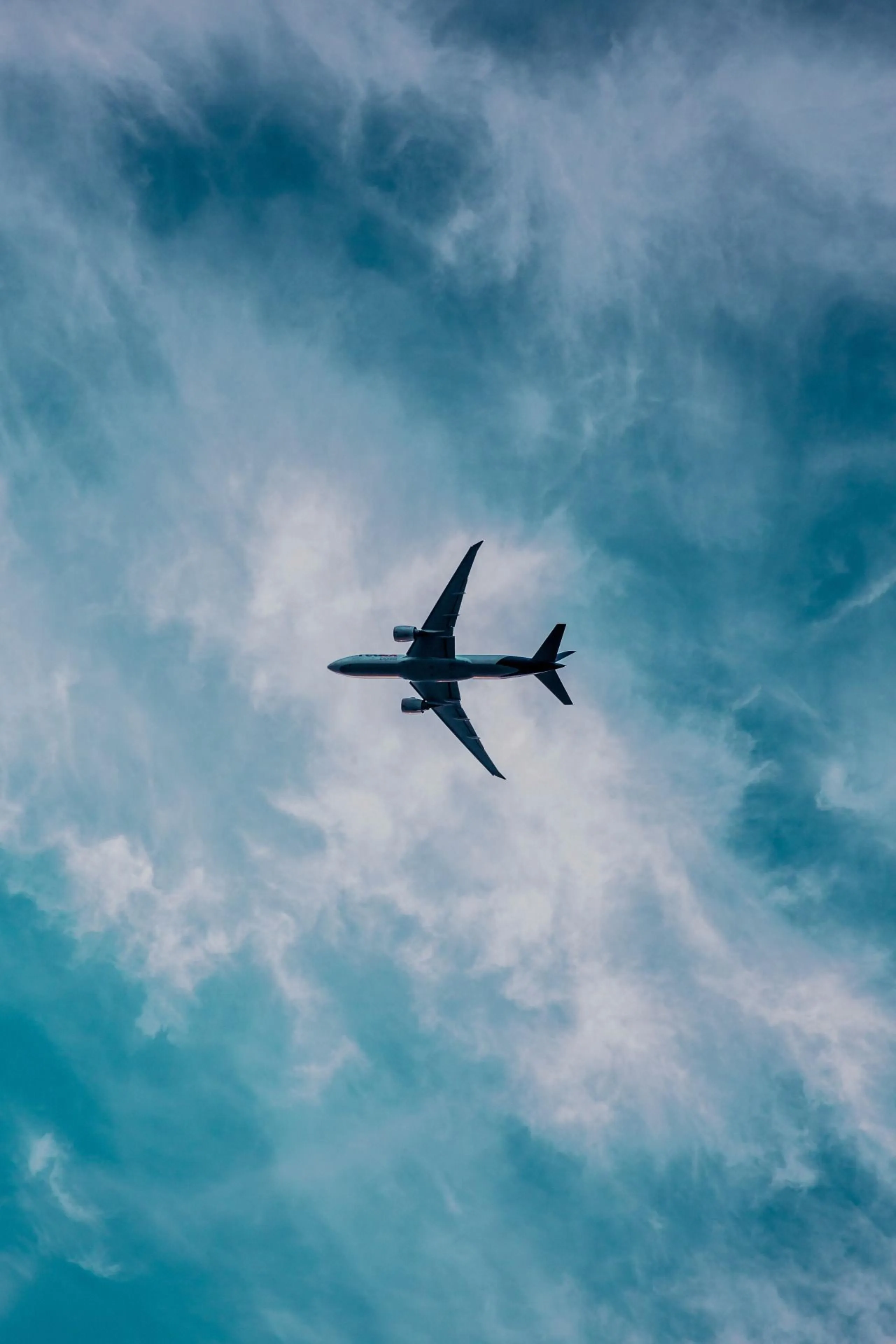 Airplane Flying High in Blue Sky with Light Cloud Cover