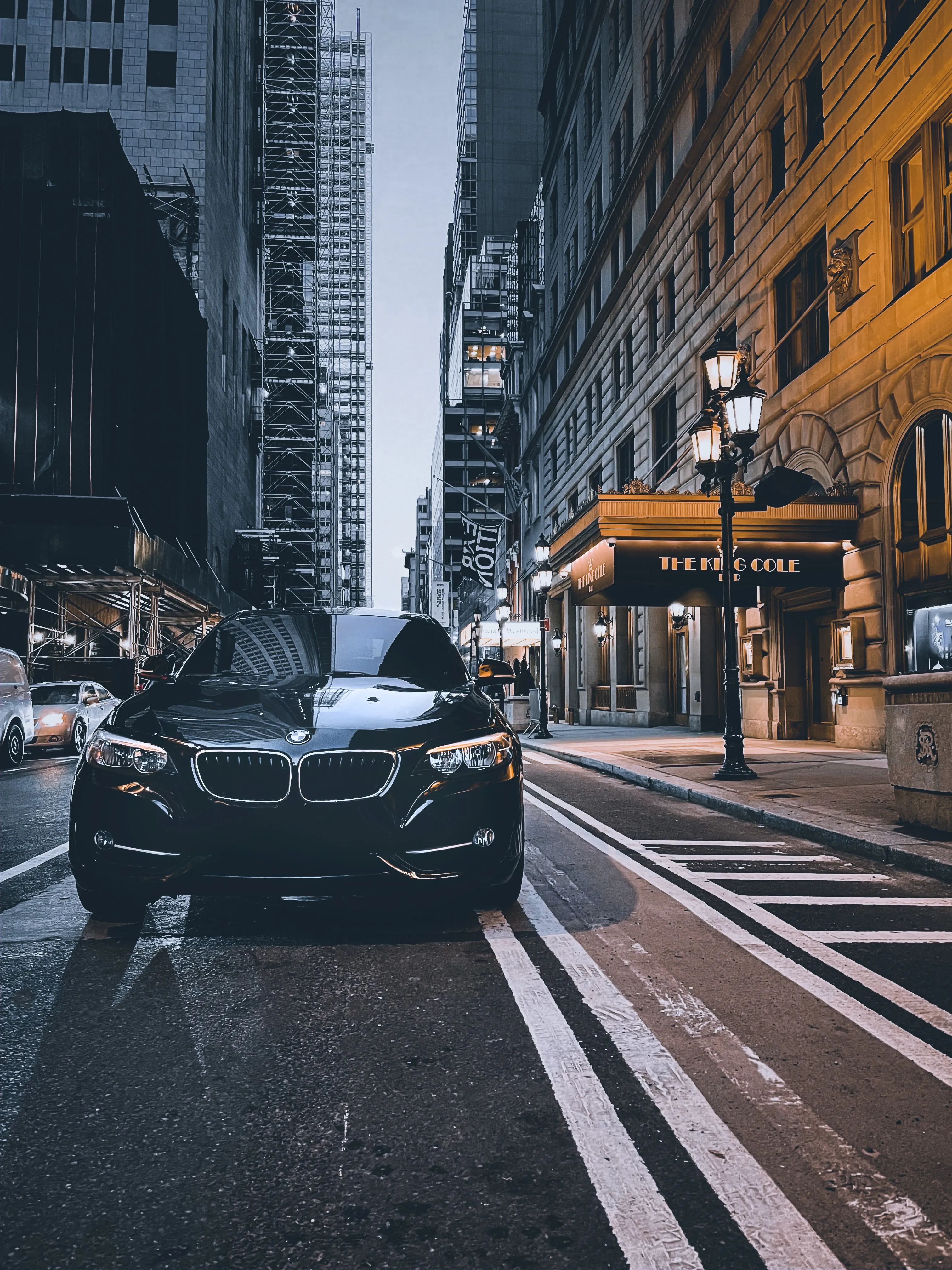 Black Car Driving Through Busy Urban City Street Wallpaper