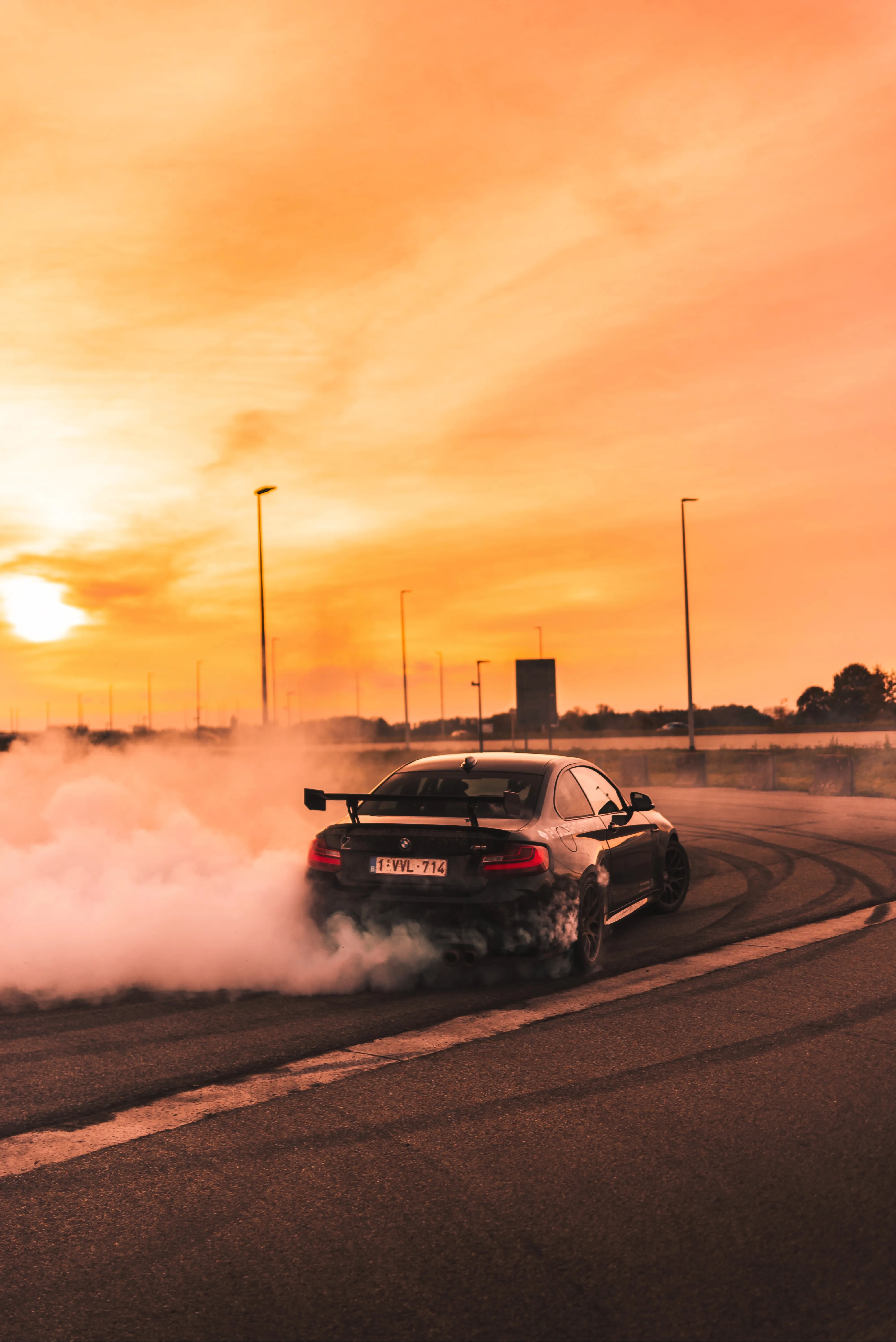 Black Car Racing Down Highway in Sunset Sky View Wallpaper