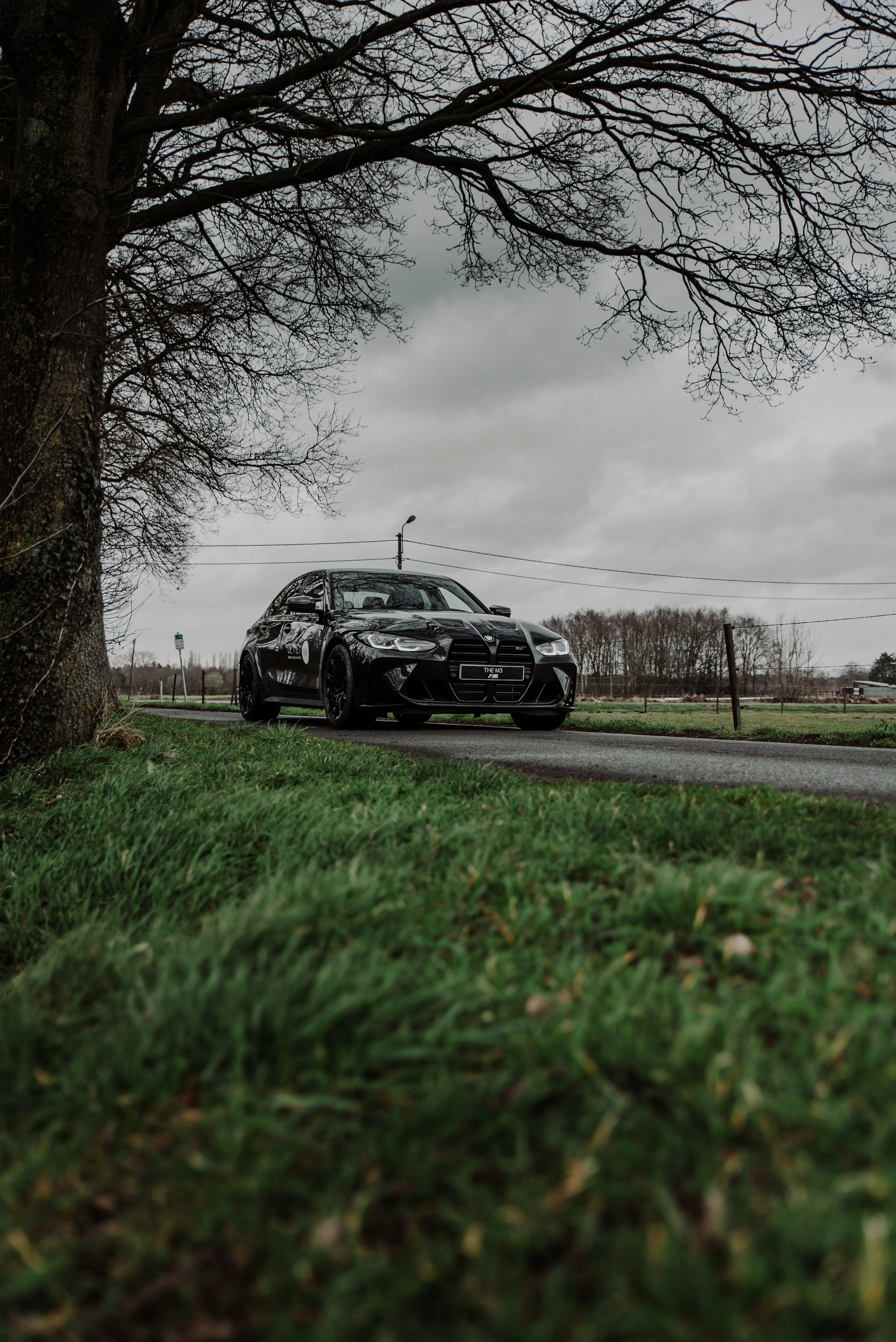 Black SUV Parked on Grassy Hill Under Cloudy Sky Wallpaper