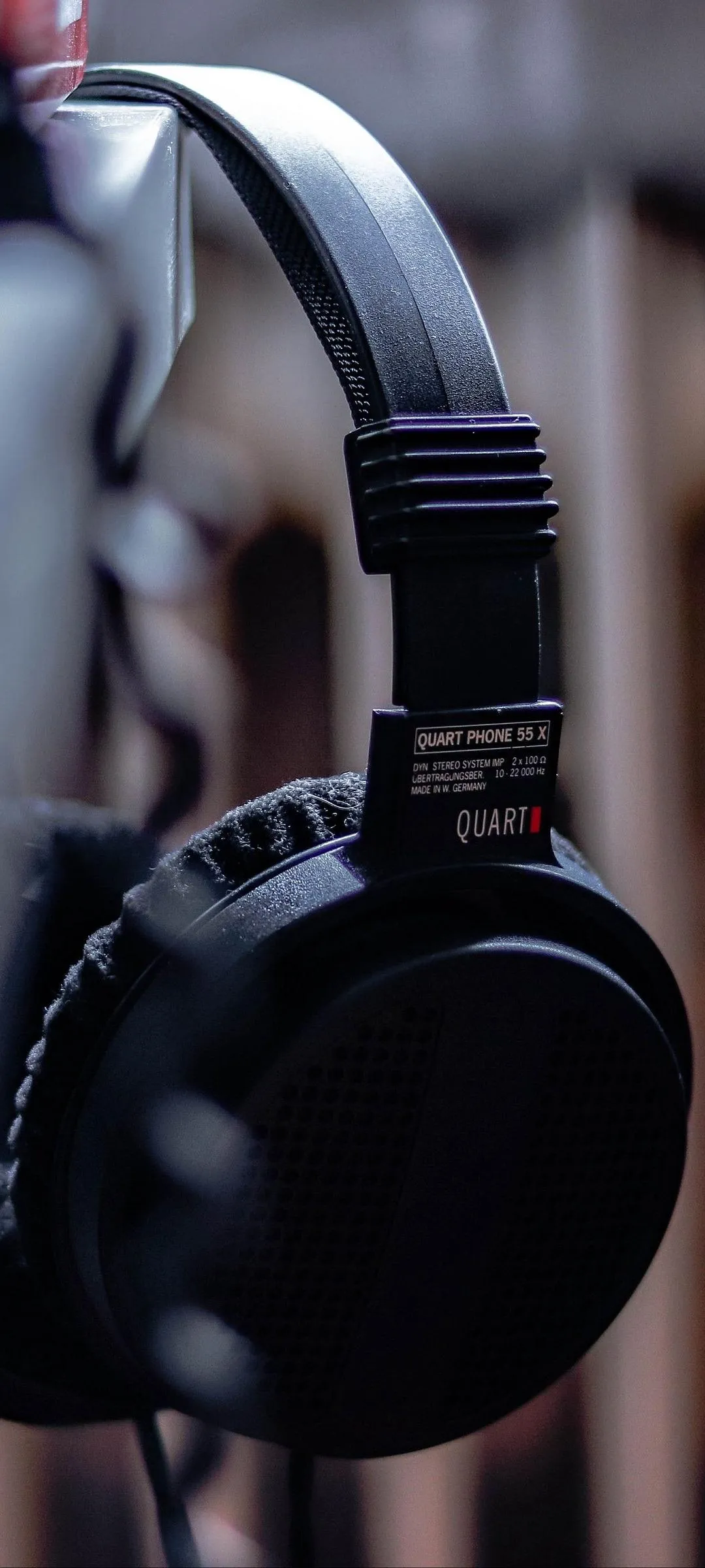 Black Wireless Headphones Hanging from Wooden Frame