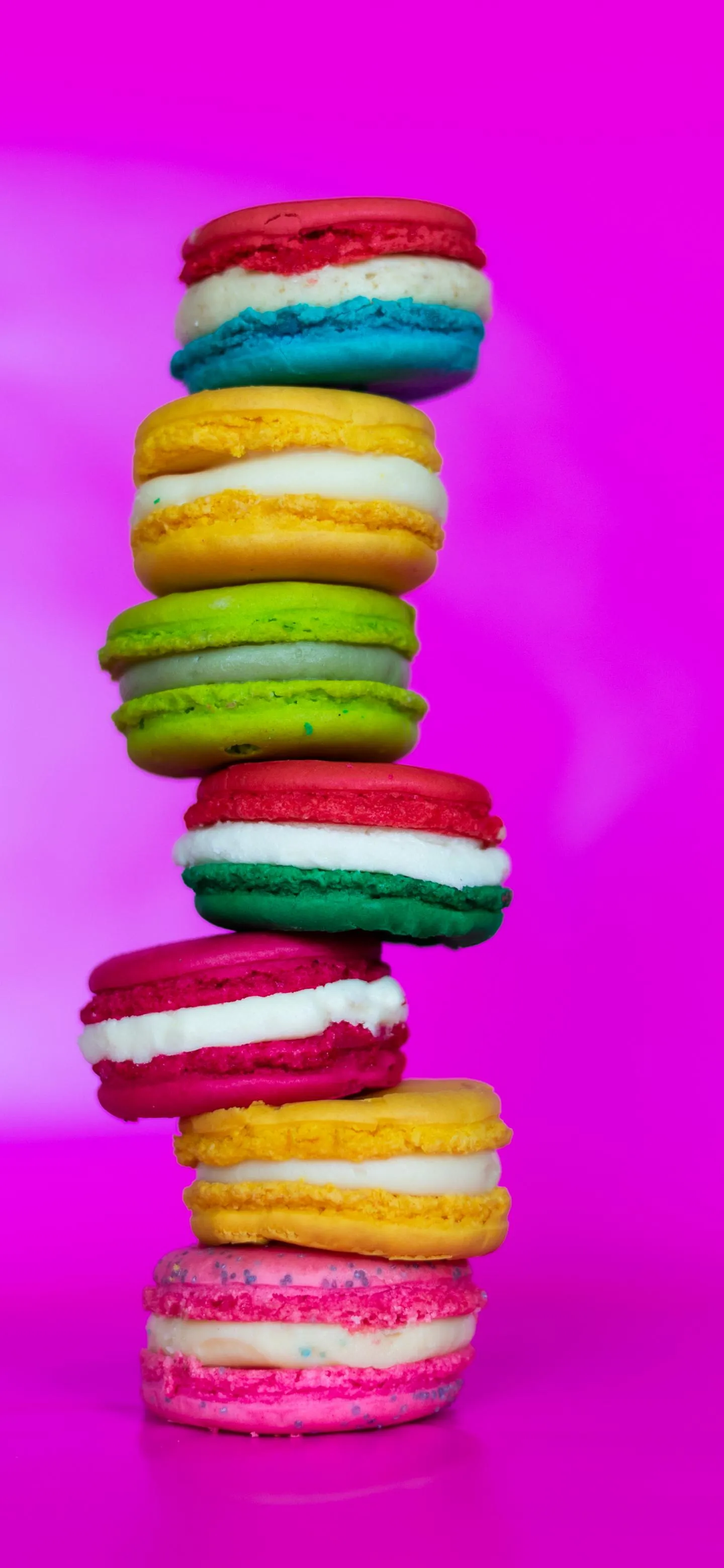 Bright Colorful Macarons Stacked on Pink Background