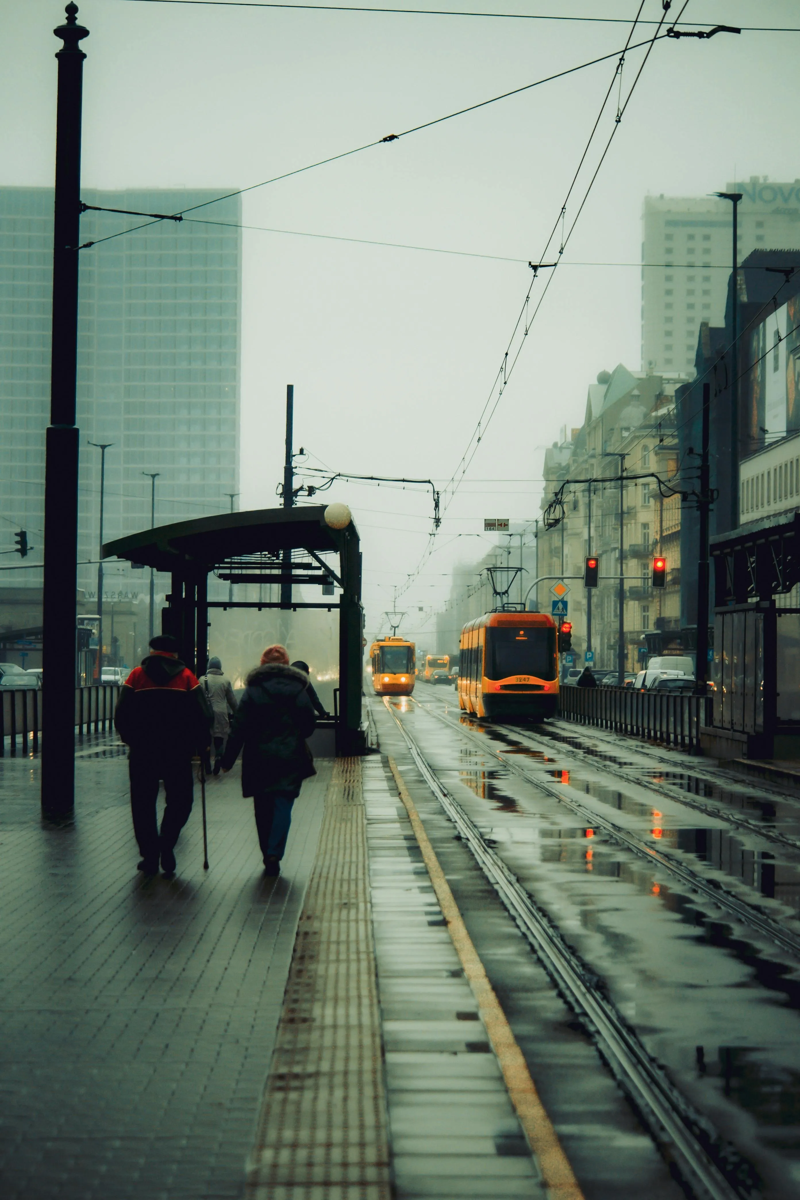 City Street Scene with Tram on Rainy Evening Road Wallpaper