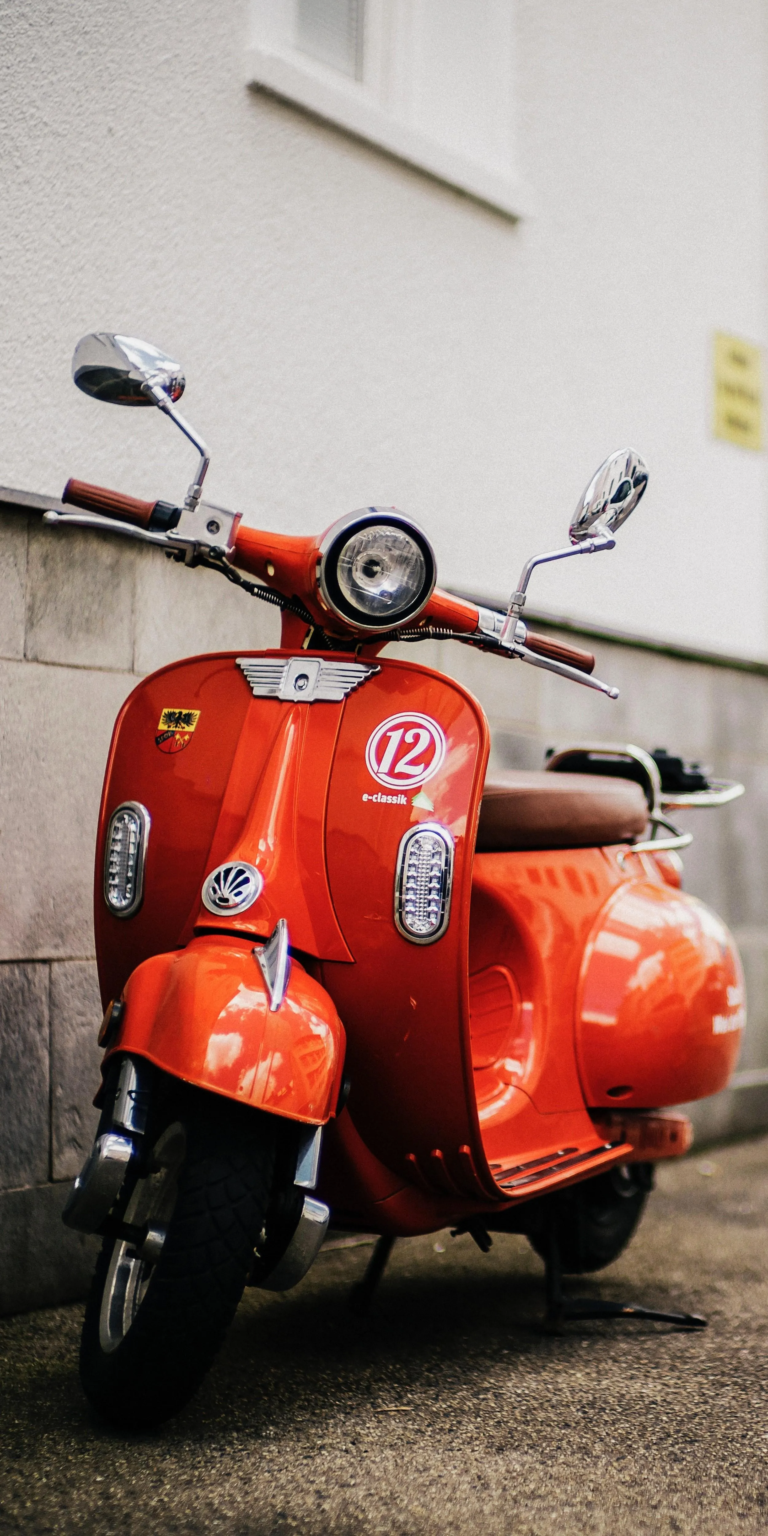 Classic Red Scooter Parked Beside a White Urban Wall