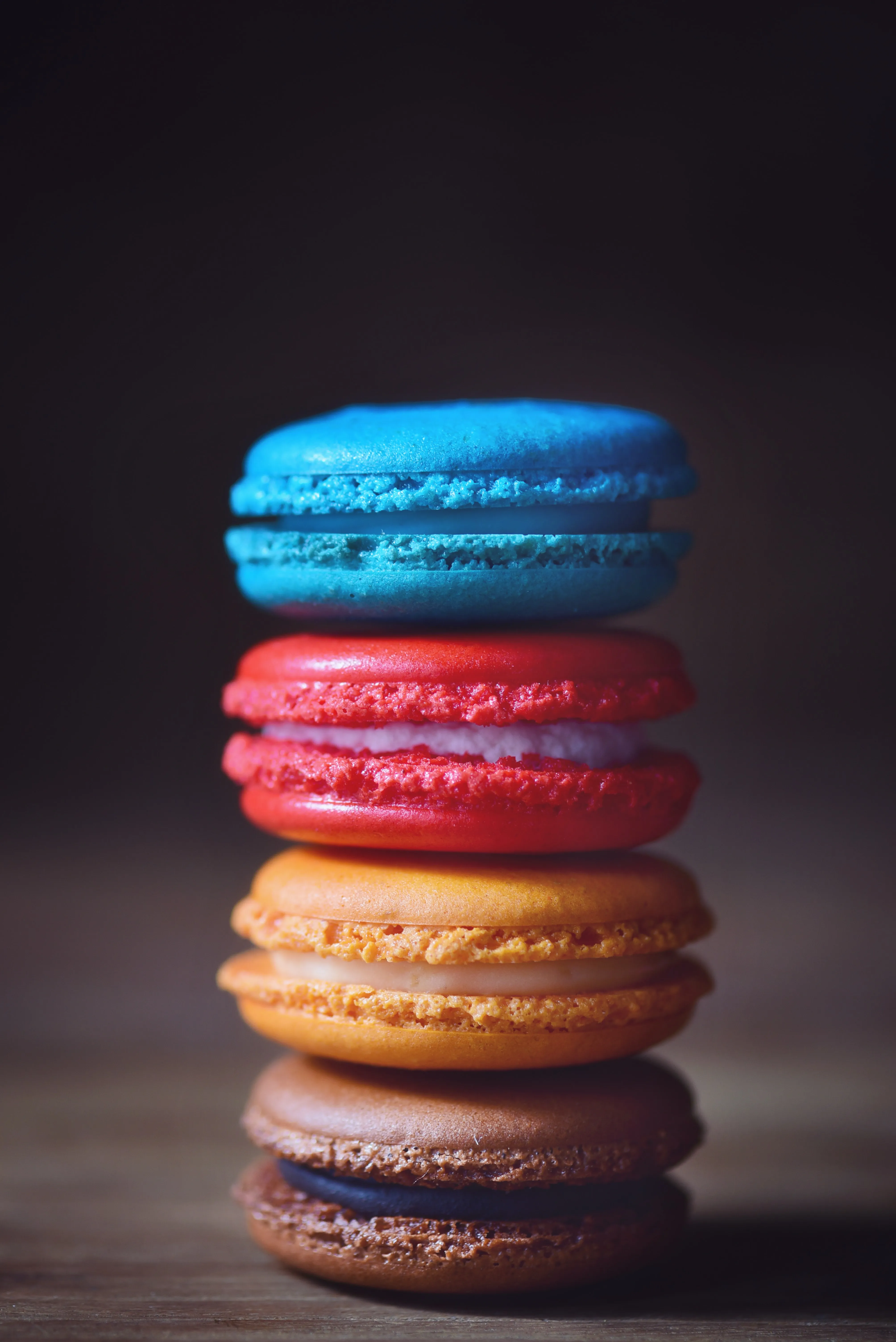 Colorful Macarons Stacked on Wooden Table Surface Wallpaper