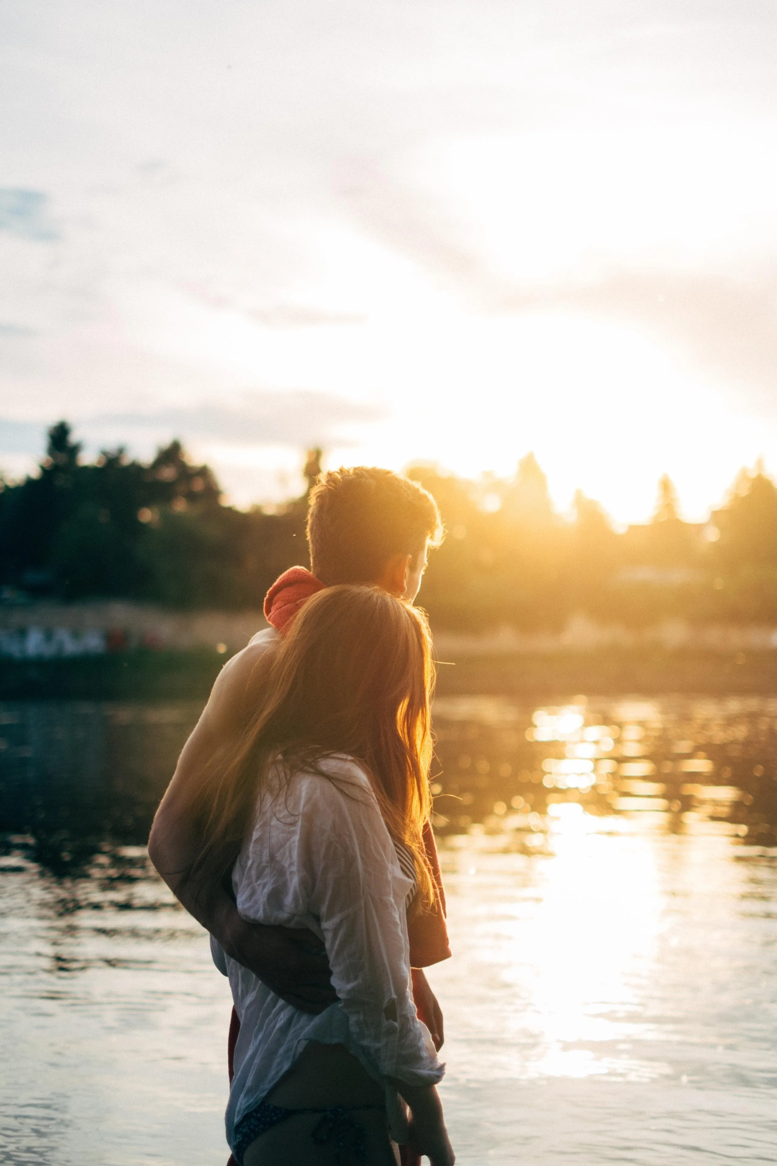 Couple Enjoying Sunset by Calm River Landscape Image