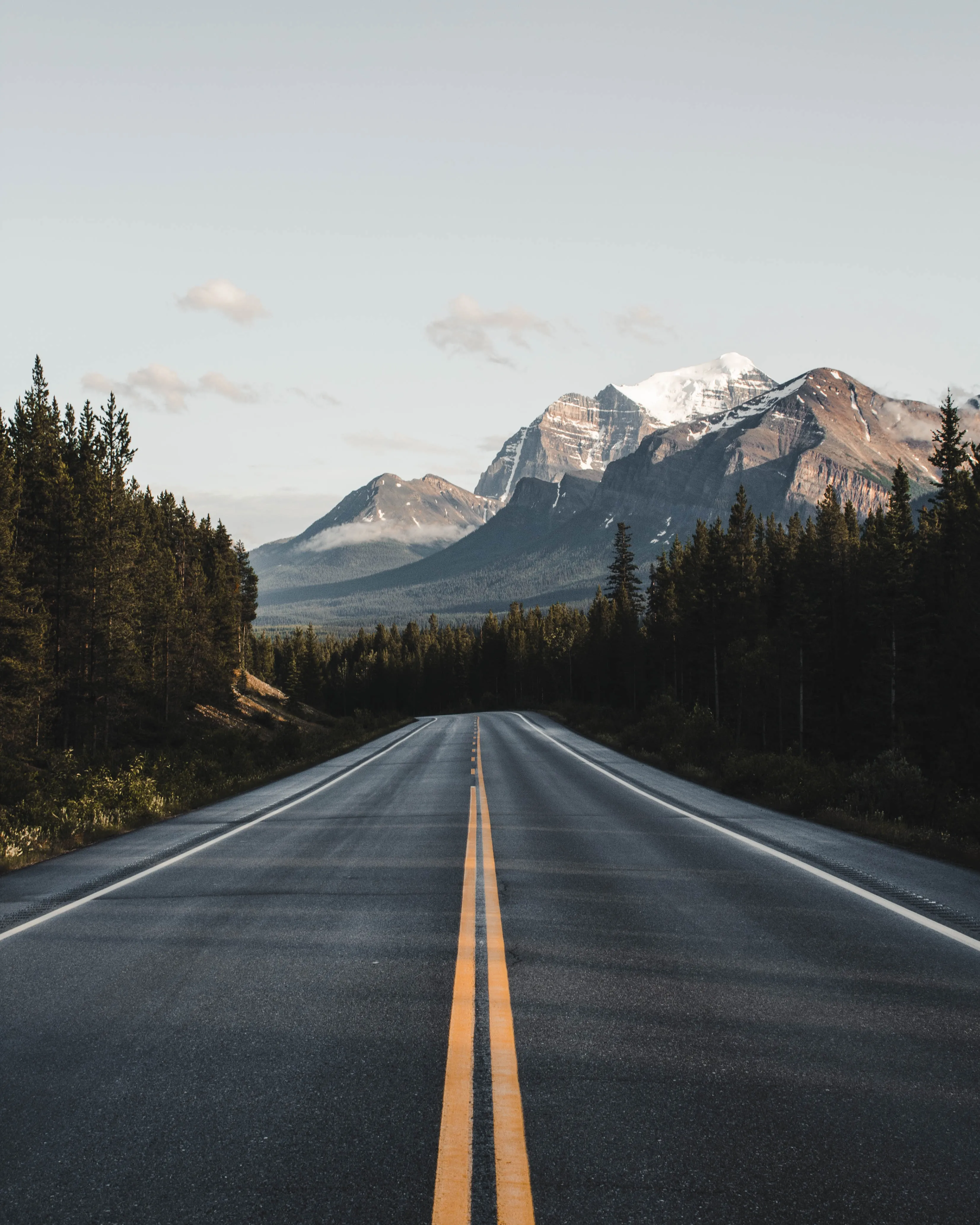Empty Mountain Road Leading to Snowy Peaks Wallpaper