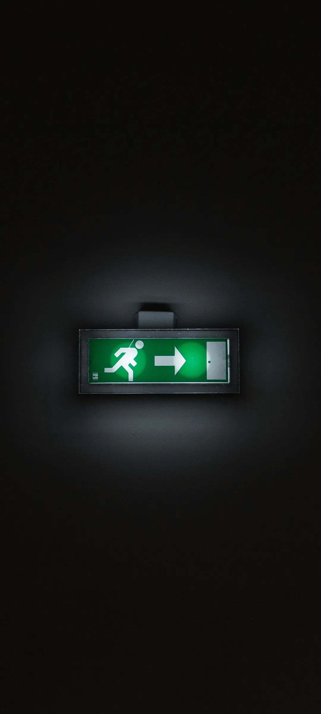 Glowing Exit Sign in a Dark and Mysterious Hall Wallpaper