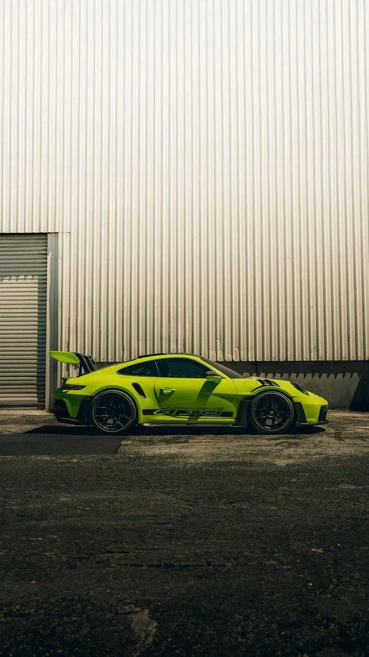 Green Supercar Parked Beside Industrial Wall HD Image