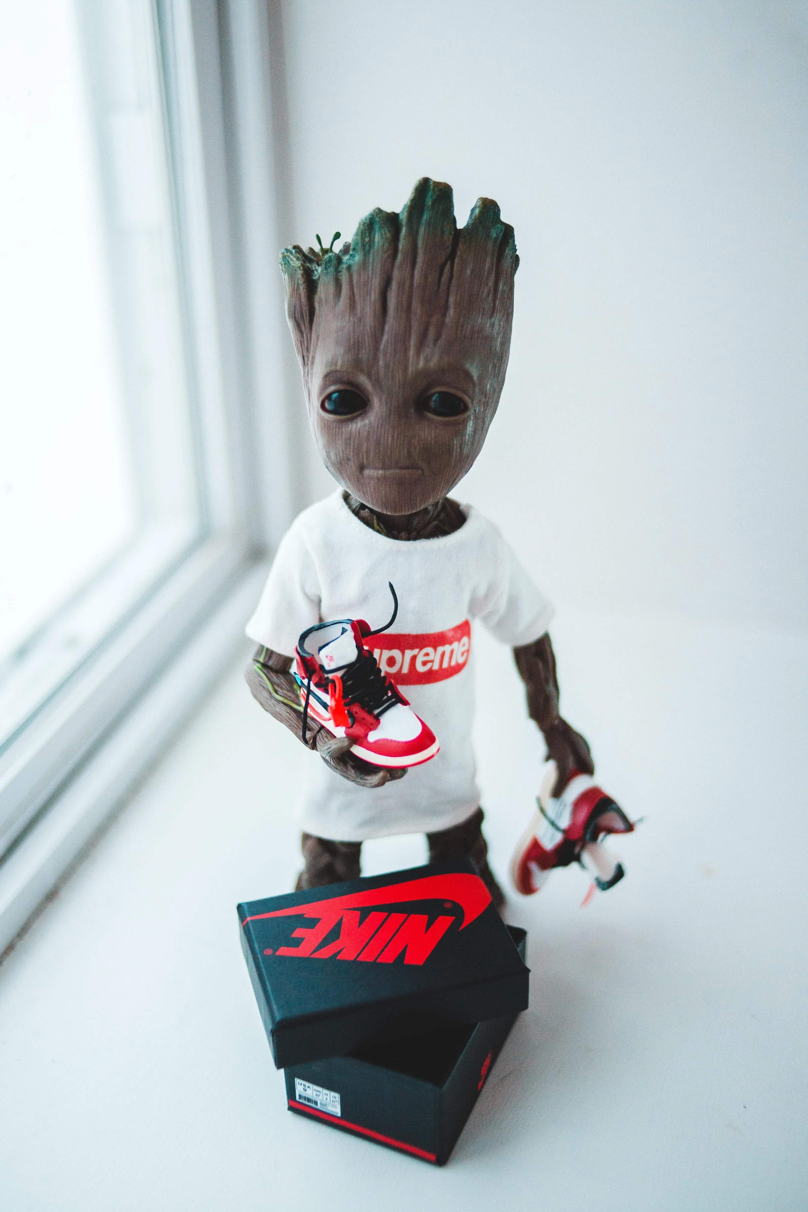 Groot Figurine Holding Red and Black Box on White Background