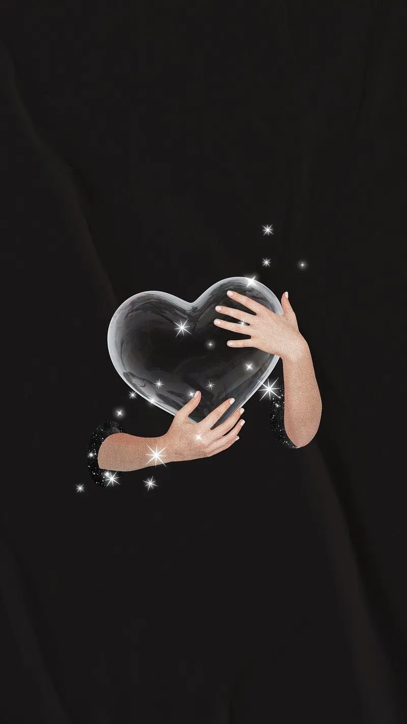Hand Holding Crystal Heart against a Deep Dark Backdrop