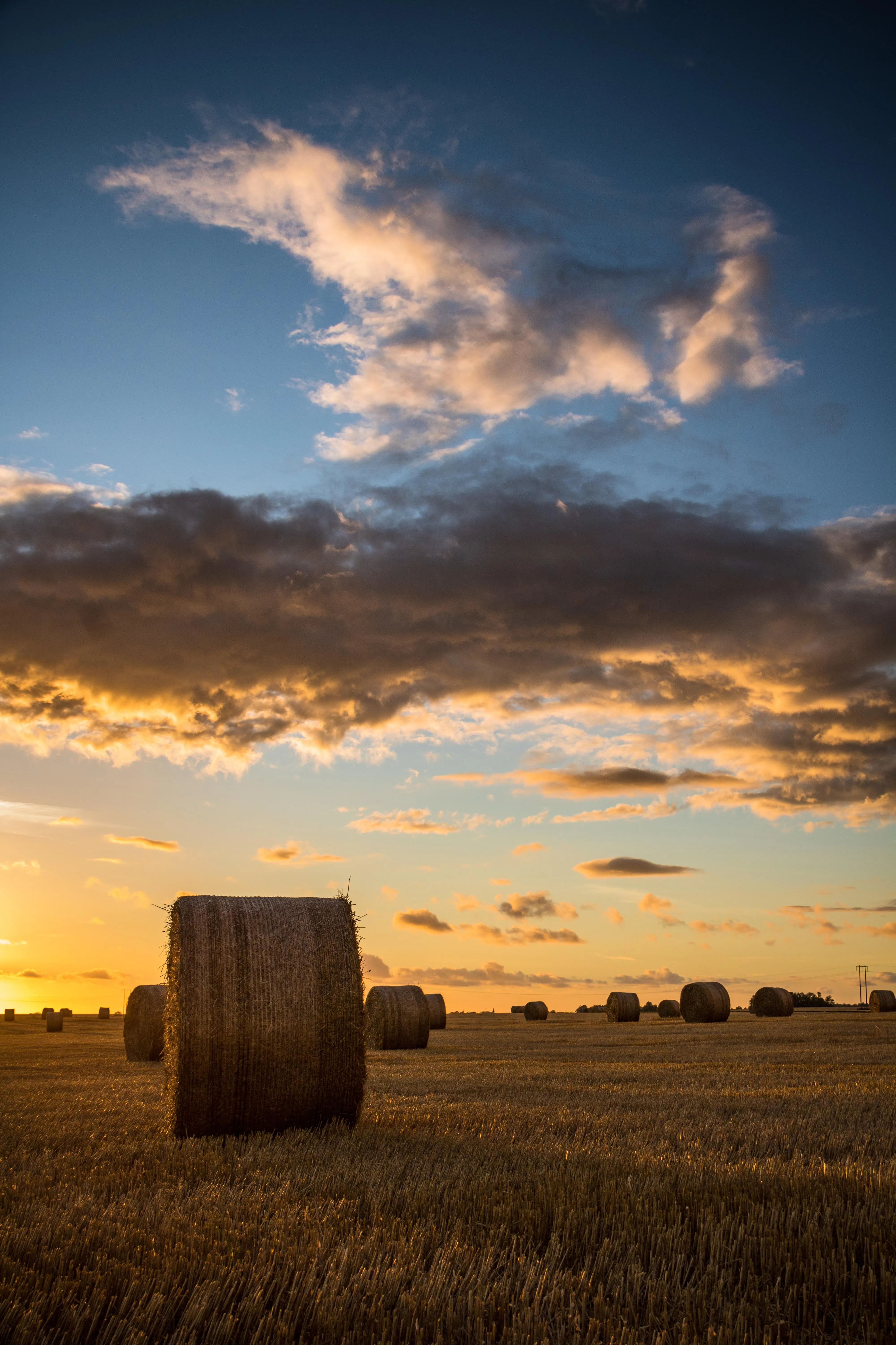 Hay Bale on Field Under Dramatic Sky at Sunset Time Image