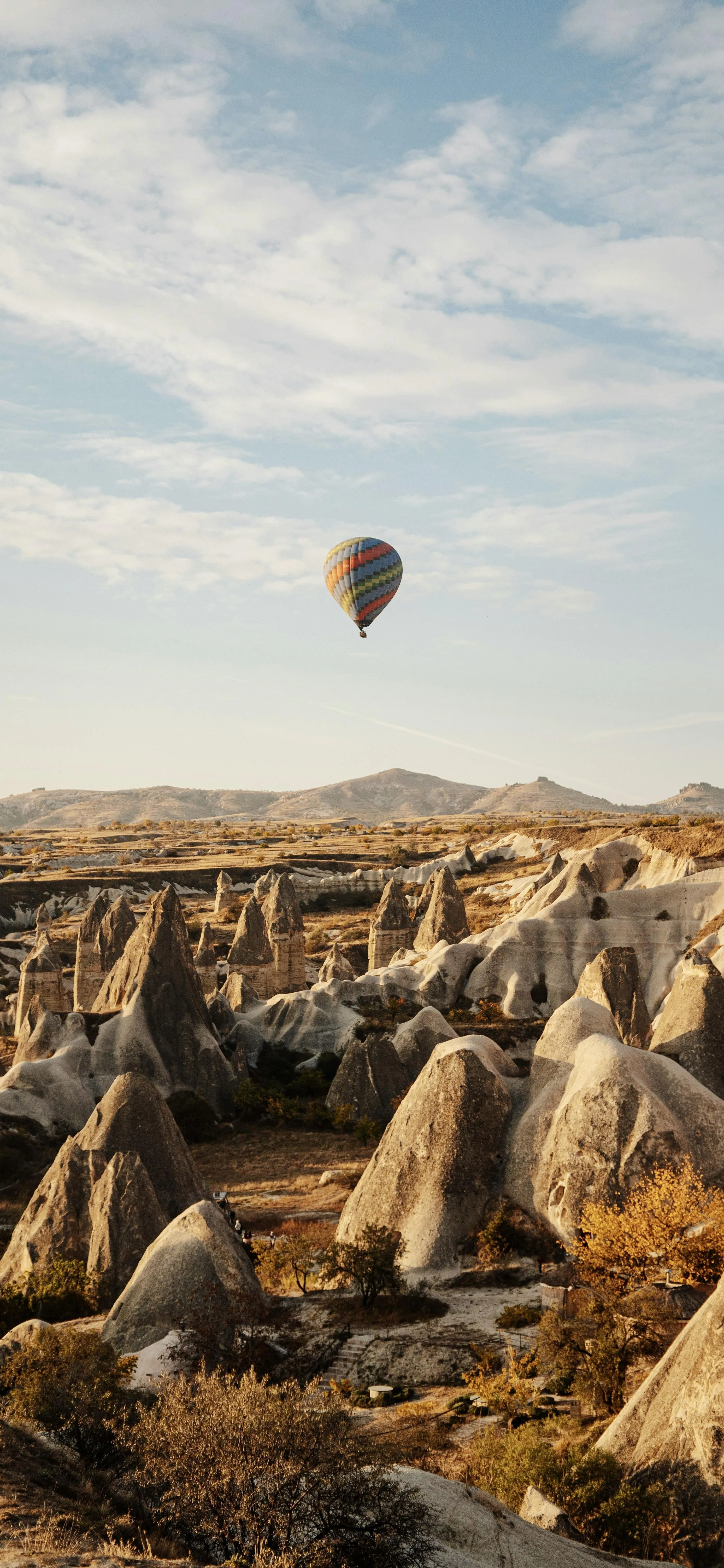 Hot Air Balloon Flying Over Rocky Landscape at Sunrise